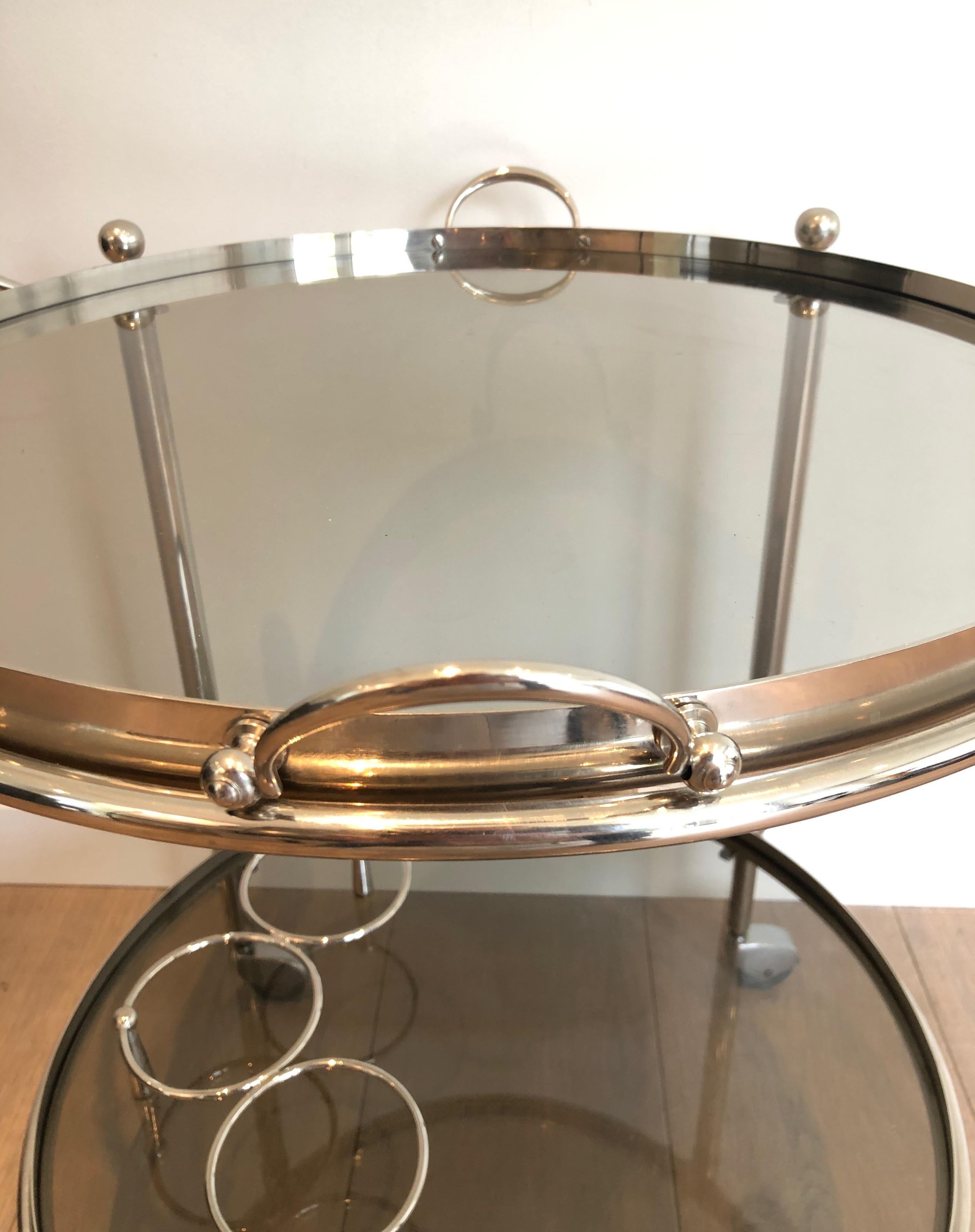 This round bar cart with removable smoked glass trays is made of silver plated. This is a French work, circa 1970.