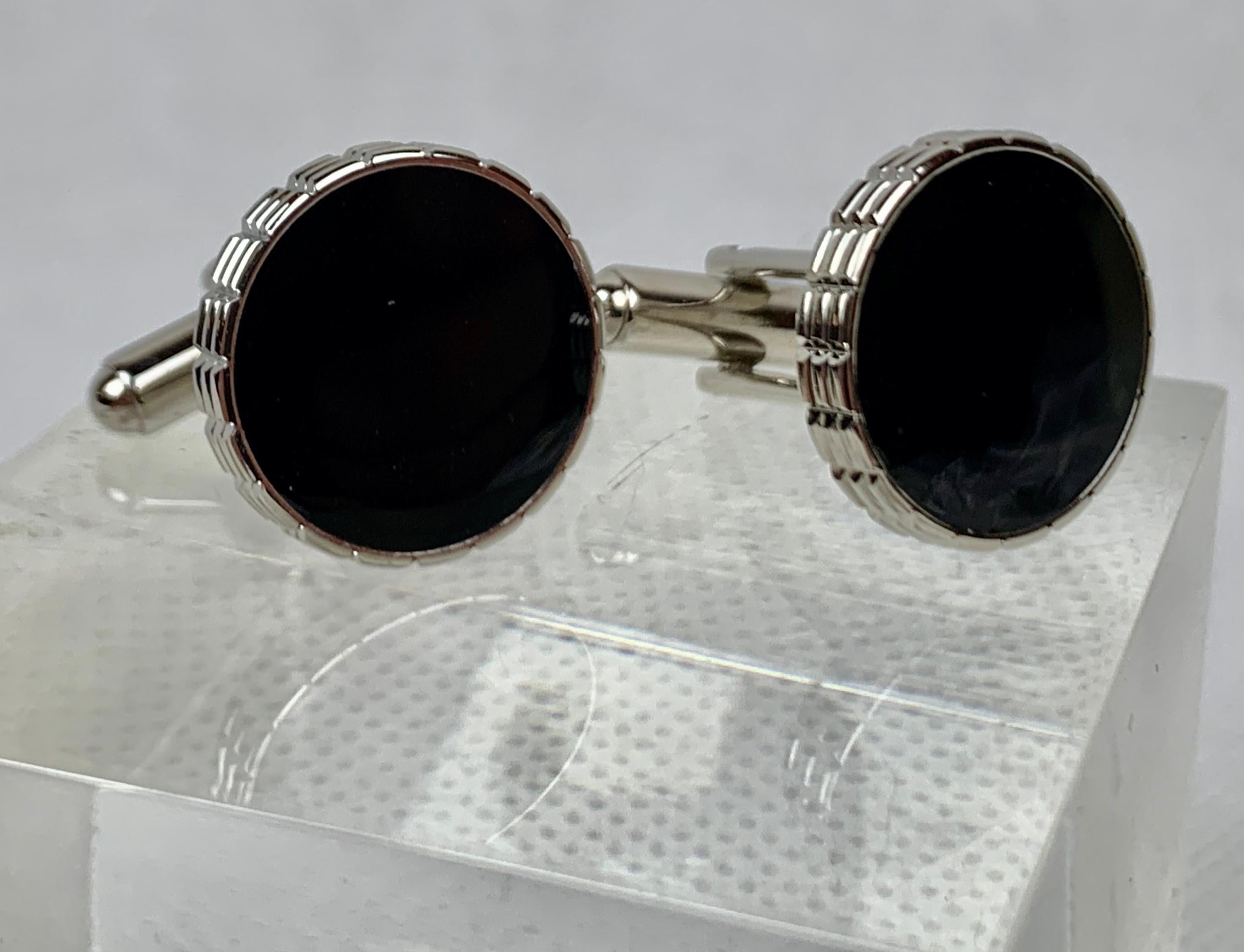 A vintage pair of round silver tone cufflinks with black enamel.  The backs are 