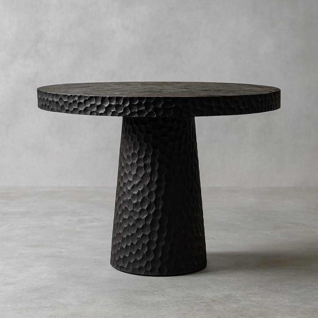 Crafted from solid oak and finished in deep black, this round dining table balances raw texture and sculptural geometry with refined modern presence. Designed by Sergio Vulpe, it merges brutalist strength with organic elegance, creating a bold yet