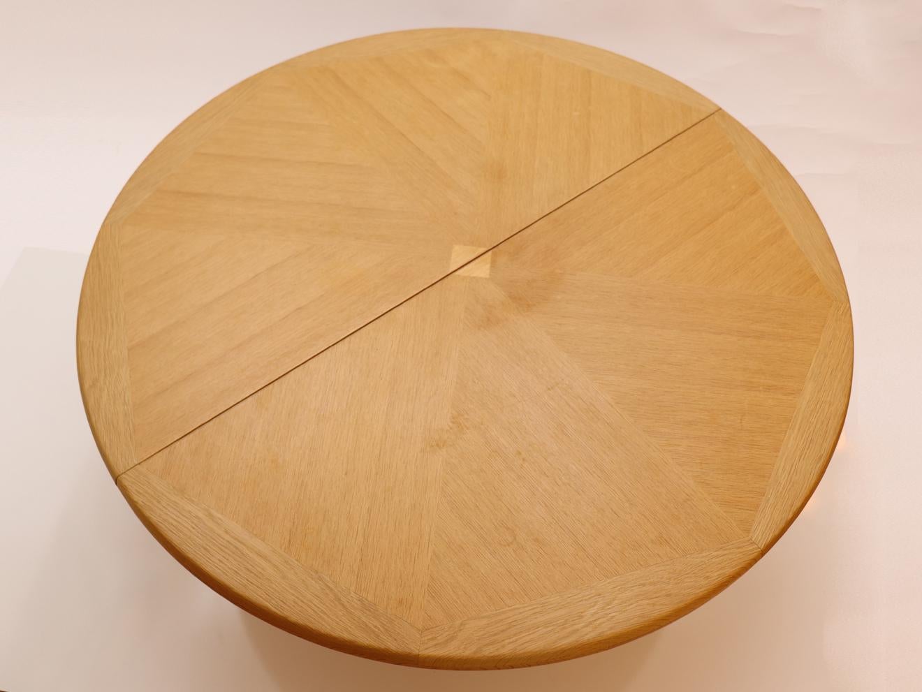 Round solid oak expanding dining table by Guillerme & Chambron, 
This stunning solid oak dining table, model Victorine is a true masterpiece of design and great crafstmanship created by the French duo Guillerme & Chambron. The table boasts a unique