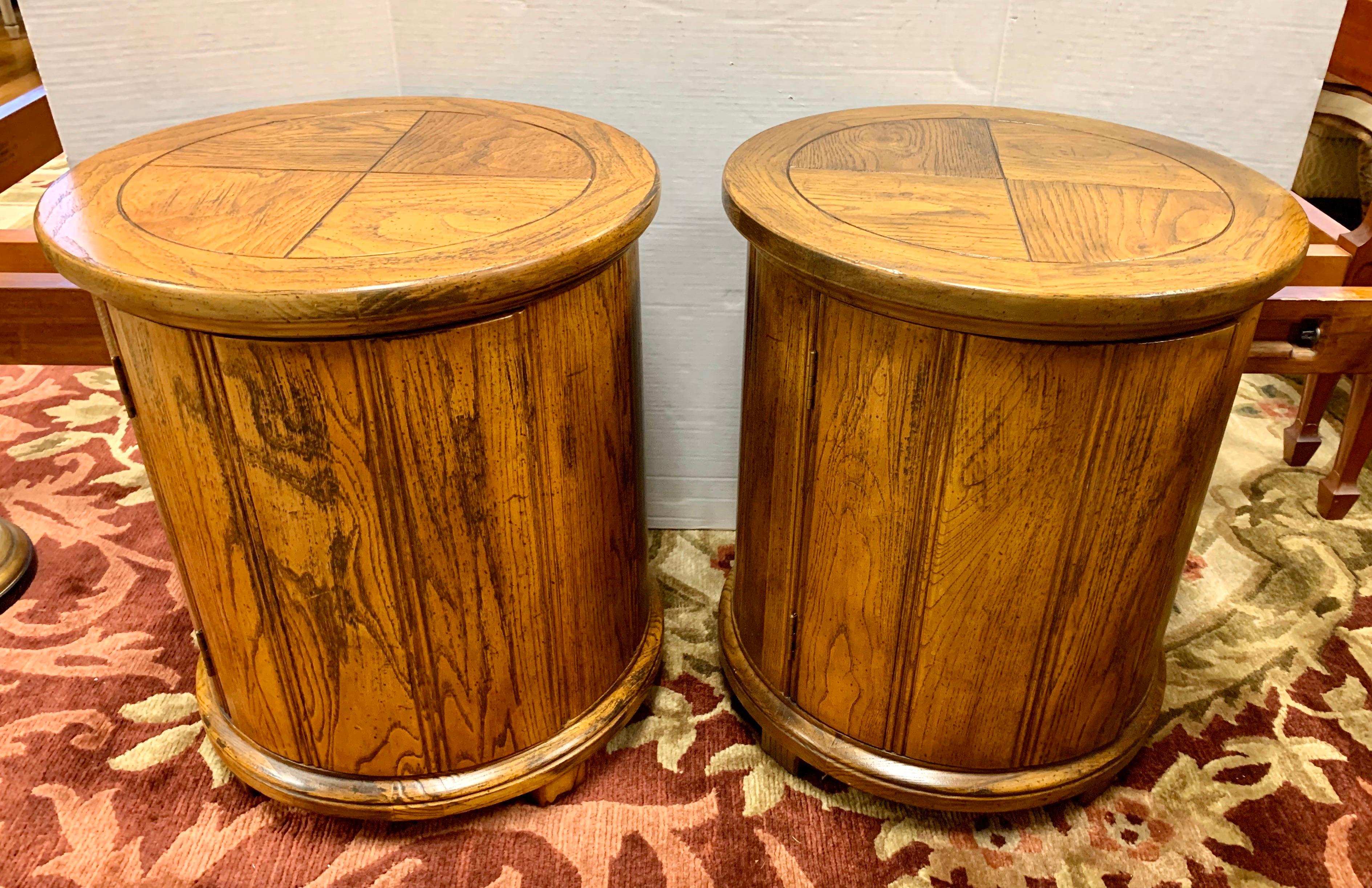 Pair of vintage wood drum end tables features circular top and base, with a single door opening to a storage space without shelving. Perfect flanking a sofa or as nightstands.