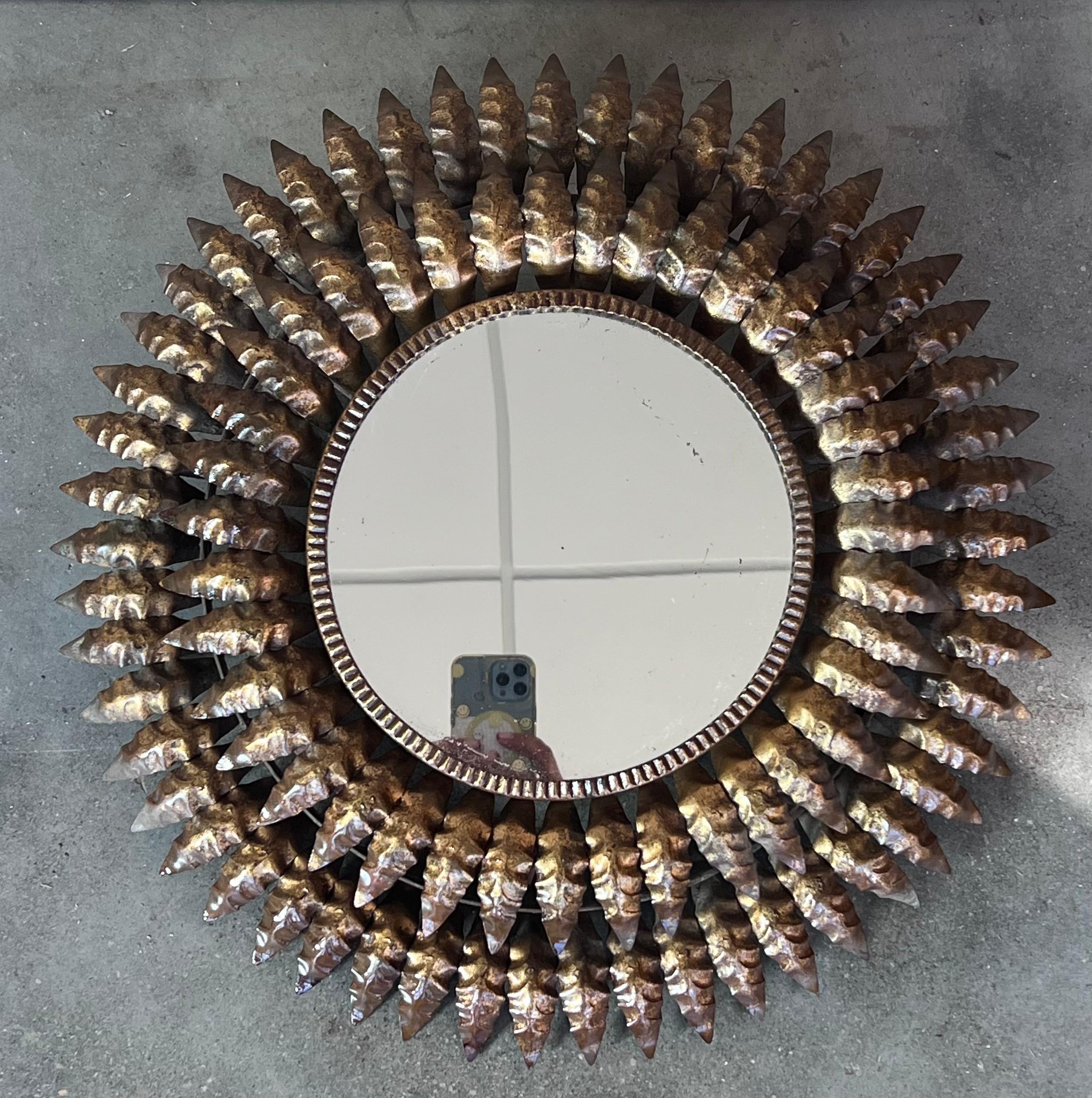 Specchio rotondo a raggiera in metallo dorato con foglie lunghe e strette unite al centro e irradiate da un bordo solido. Il vetro è originale e mostra i segni dell'età. Spagnolo anni '50. Condizioni vintage molto buone.

Lo specchio misura 22,5 cm.