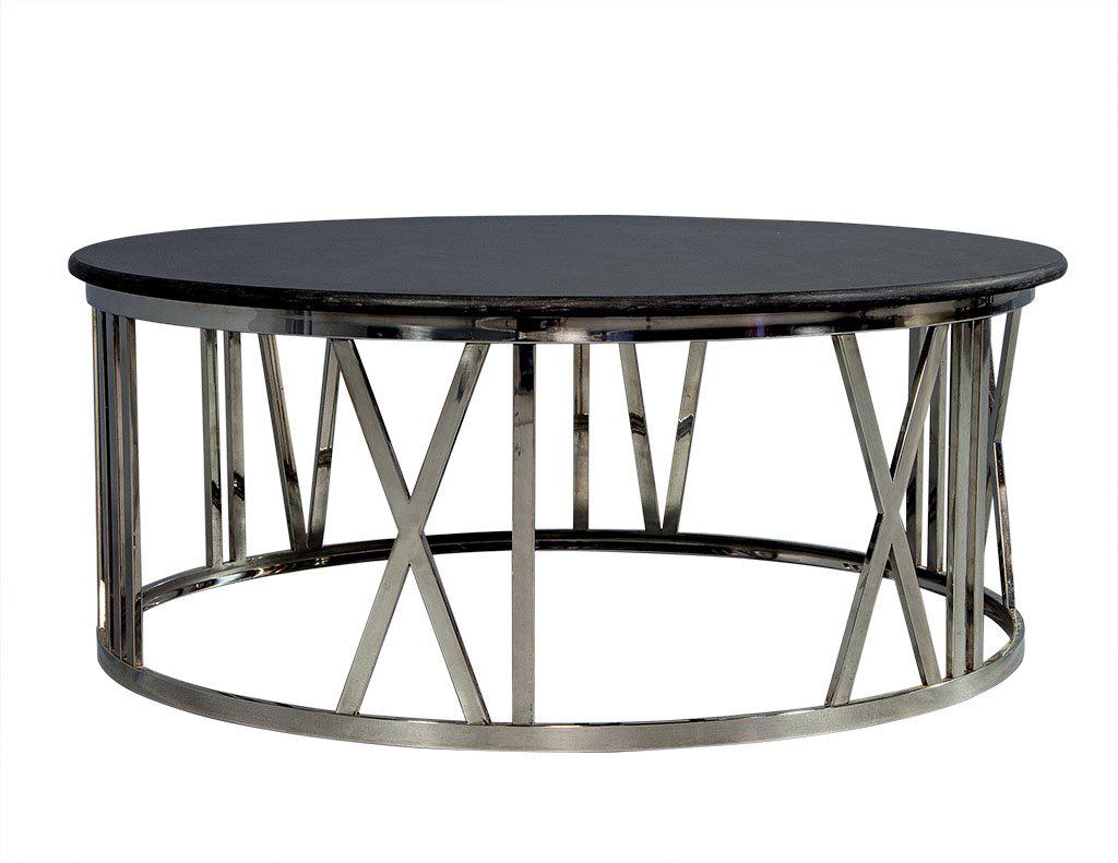 Natural and man-made materials combine to make this polished stainless steel cocktail table with a black honed stone top. With clean simple lines, the round drum base displays roman numerals on the exterior.