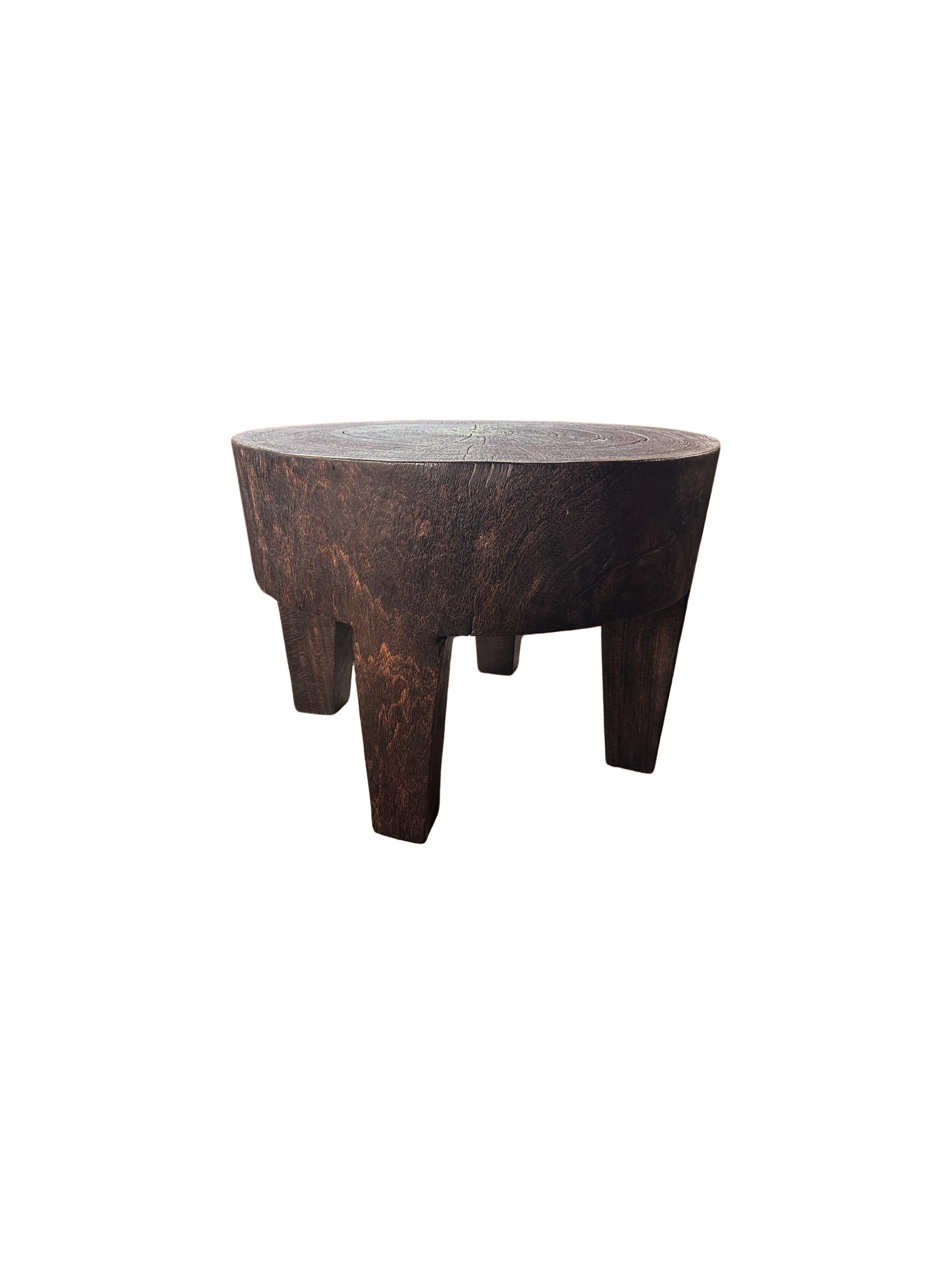 A wonderfully sculpted side table, crafted from a single block of Suar wood. It features wonderful wood textures as well 4 carved legs. The item was sanded and smoothed. To achieve its brown color the wood was burnt numerous time and finished with a
