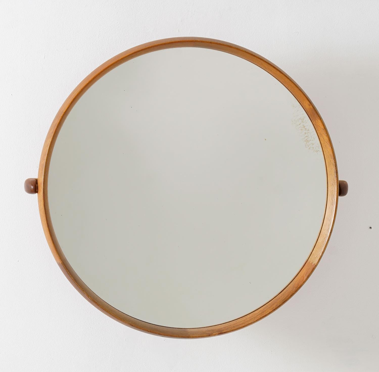 Beautiful round midcentury mirror by Uno & Östen Kristiansson for Luxus, Sweden.
The wall-mounted mirror with a swivel arm is made in teak with details in oak. 

Condition: Very good condition with signs of age on the mirror glass (a few spots).
