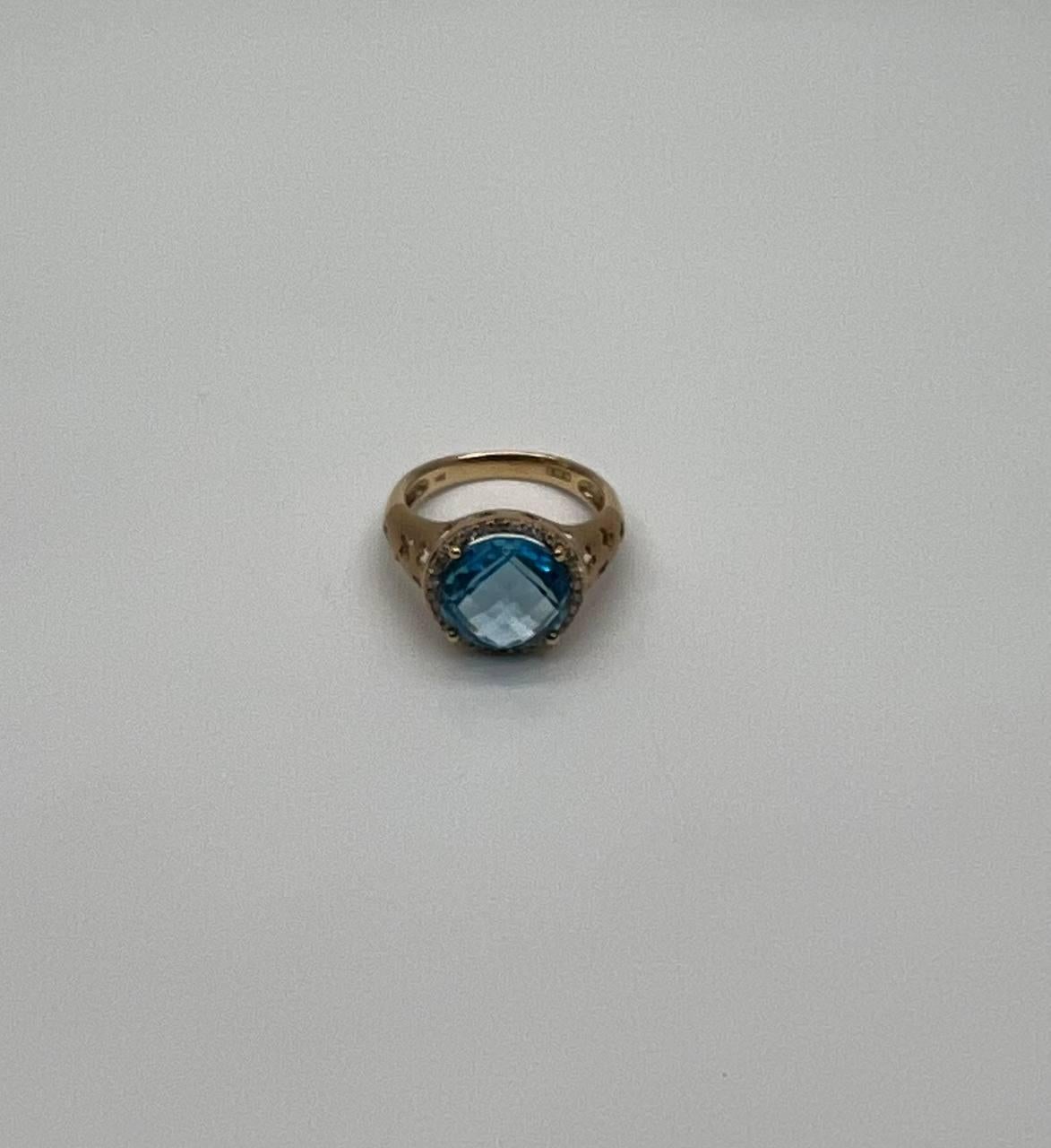 Radiant Elegance and Craftsmanship.
Set with a Faceted Blue Topaz 6.00 Cts
Encircled by a Halo of Sparkling Diamonds 0.25 CTW
Intricate Gold Band with Delicate Cutout Design.
14K Yellow Gold