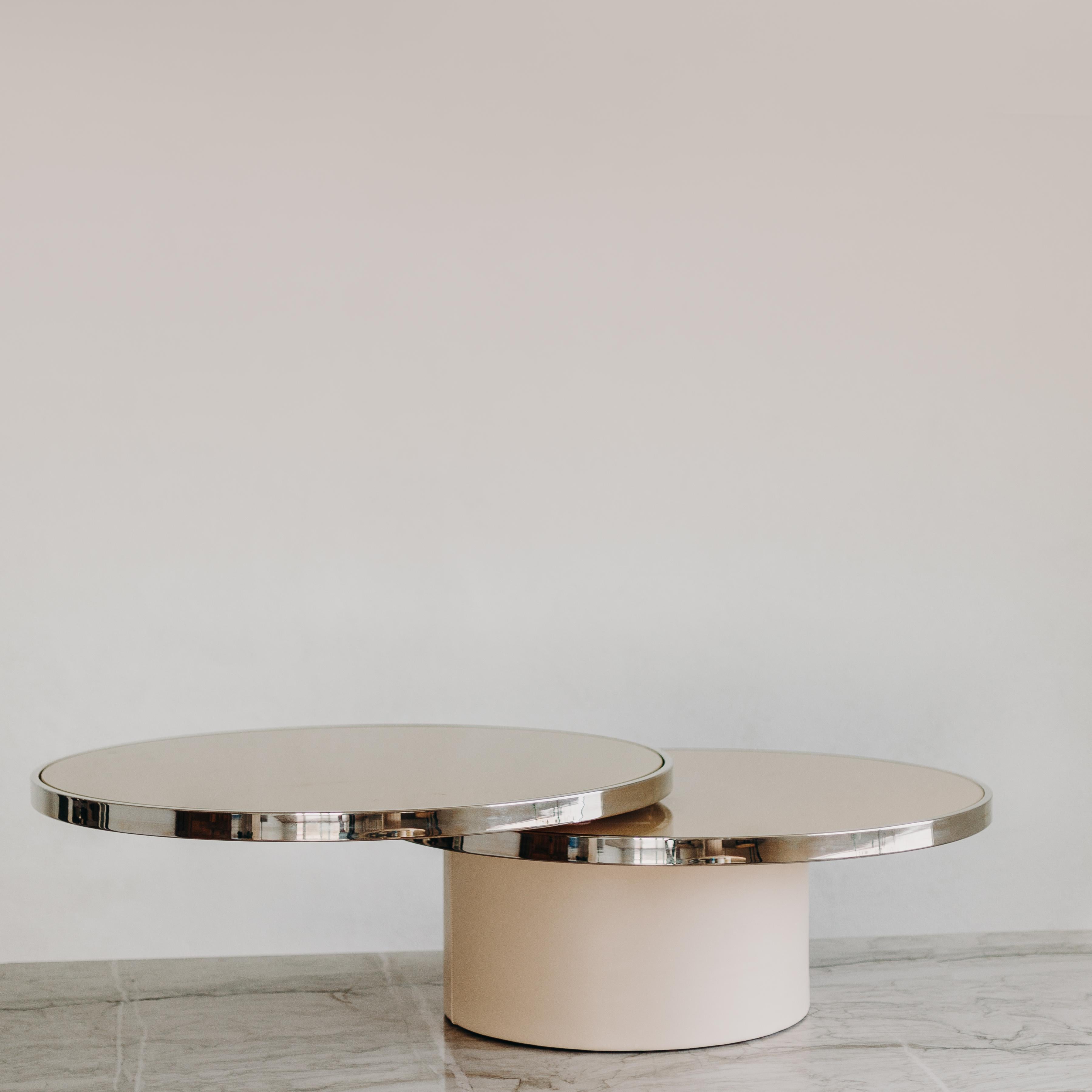 Stunning piece by the Design Institute of America. The two tier painted ivory glass tops revolve with ease. The chrome banding and suede covered drum base make for a timeless elegant piece that will suit a variety of decor styles.