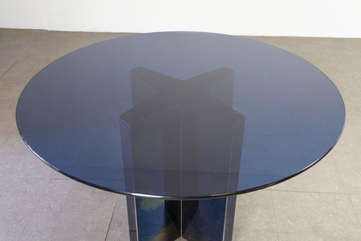 Raro modello di tavolo disegnato da Tobia Scarpa per B&B, particolarità di questo modello è la verniciatura del metallo sulla base che a seconda dei cambi di luce ha sfumatura che vanno dal blu al verde scuro.
Il piano è in cristallo blu.
Questo