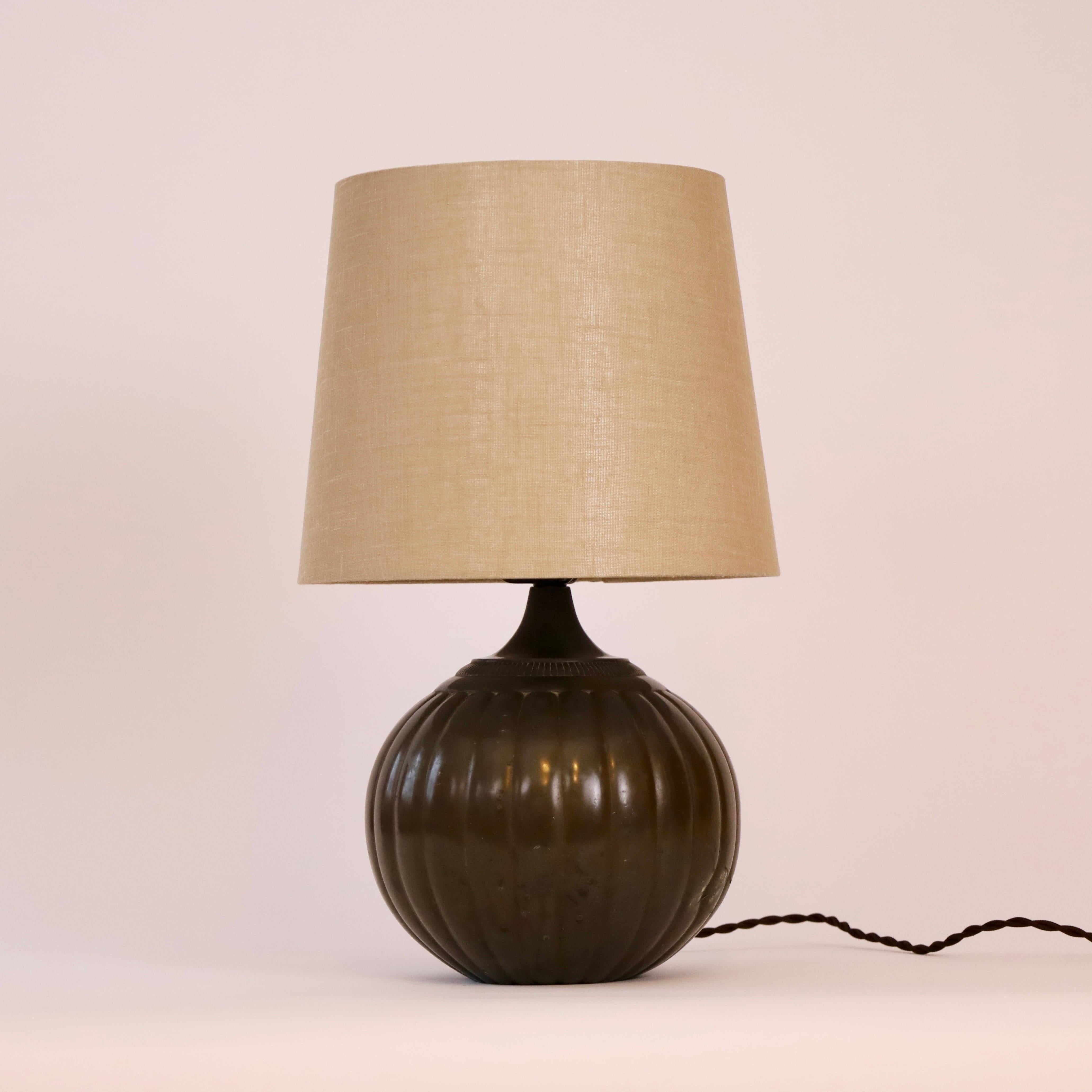A rare table lamp designed by Just Andersen in 1934. A classic piece of Danish design history for a beautiful home.  

* A round metal lamp with vertical lines and a beige fabric shade
* Designer: Just Andersen
* Model: 1632 (stamped ‘Just 1632’)
*