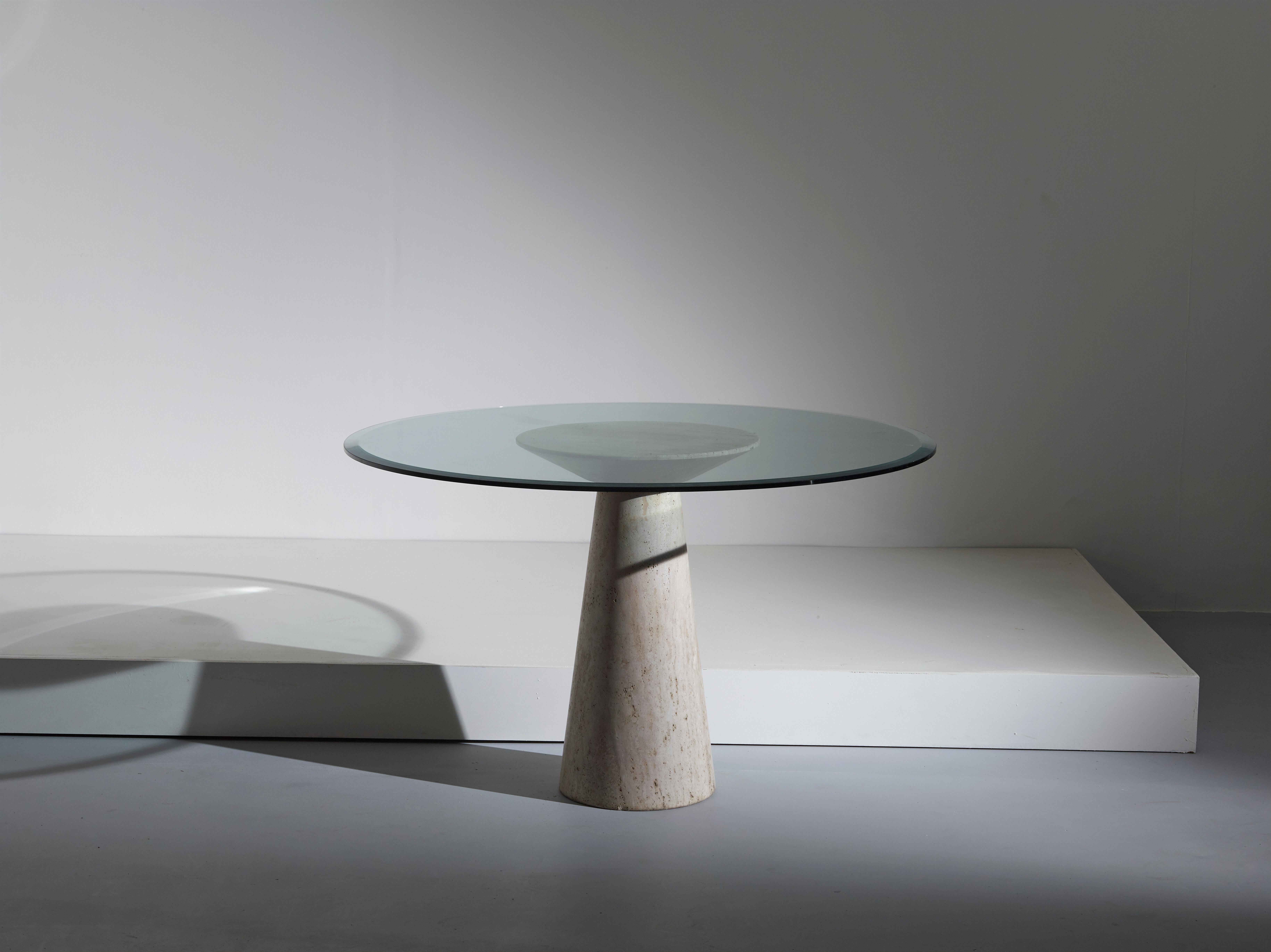 A beautiful round dining table with glass top attributed to Angelo Mangiarotti. The travertine stone used on the base emphasises and – at the same time – eases the classical but linear shape of this piece. 
This example has been produced in the