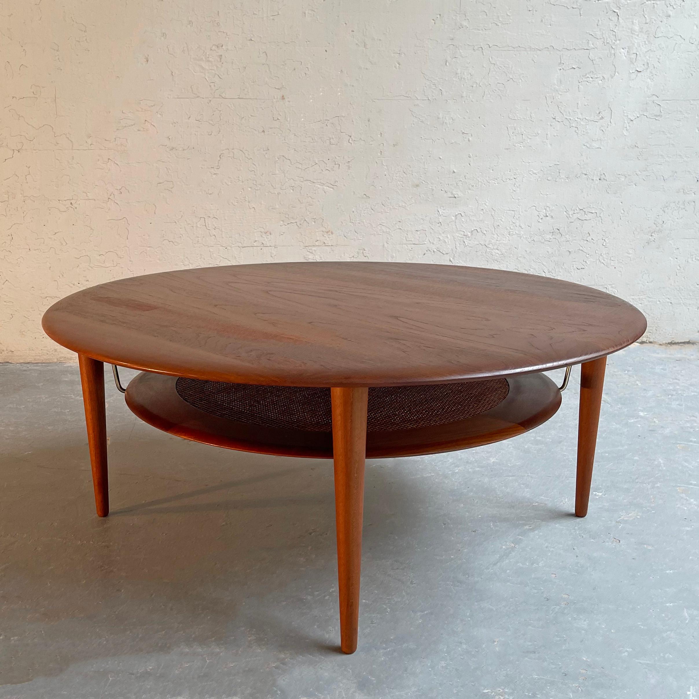Danish modern, model 515, round, teak coffee table by Peter Hvidt and Orla Molgaard Nielsen for France & Søn/France & Daverkosen features a lower caned tier with brass braces.
