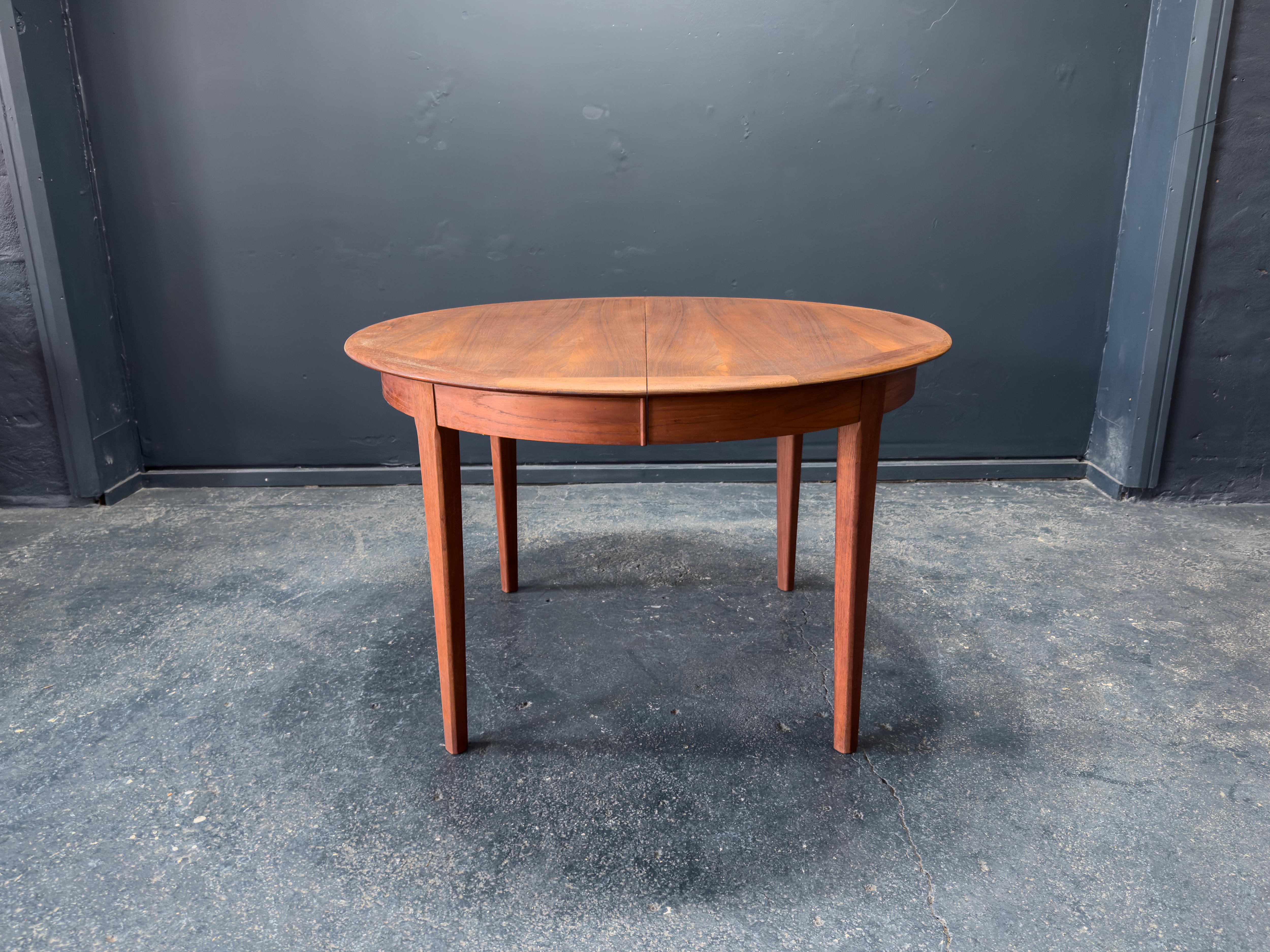 Questo tavolo da pranzo in teak di ottima fattura presenta dettagli di design eccezionali e una raffinata falegnameria, particolarmente visibile nel suo bordo elegantemente costruito. Il piano rotondo del tavolo è accentuato da un caratteristico