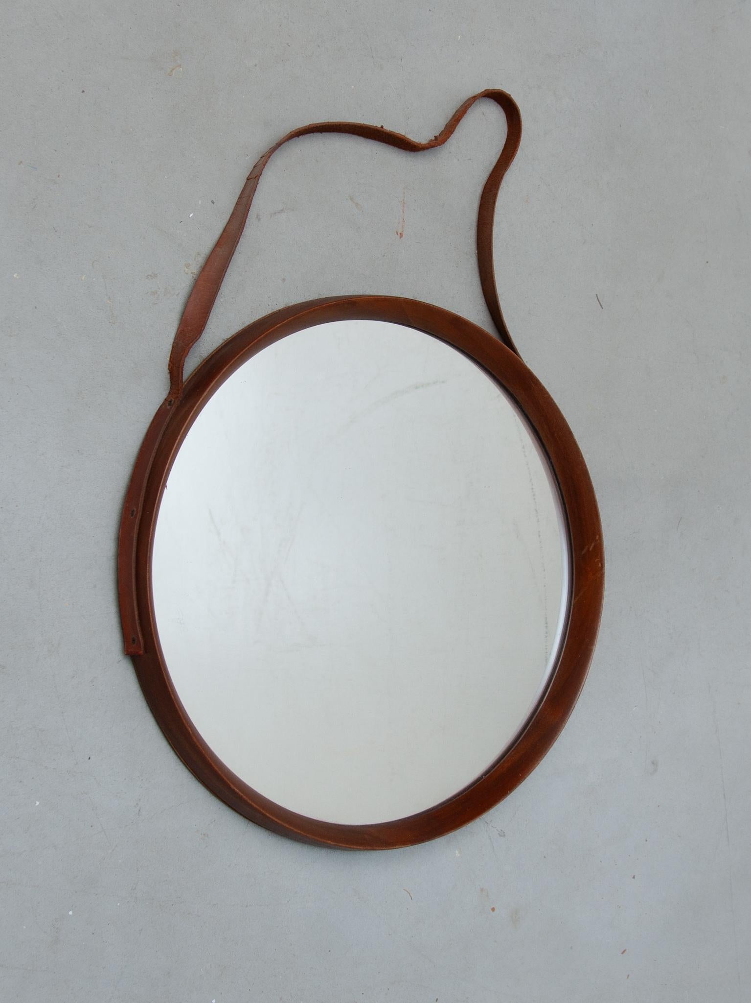 A beautiful round mirror in teak, manufactured in Denmark in the 1960's. 
The joinery is a sign of true craftsmanship. The mirror is in very good vintage condition. The leather hanging for the mirror has deteriorated through use and time.