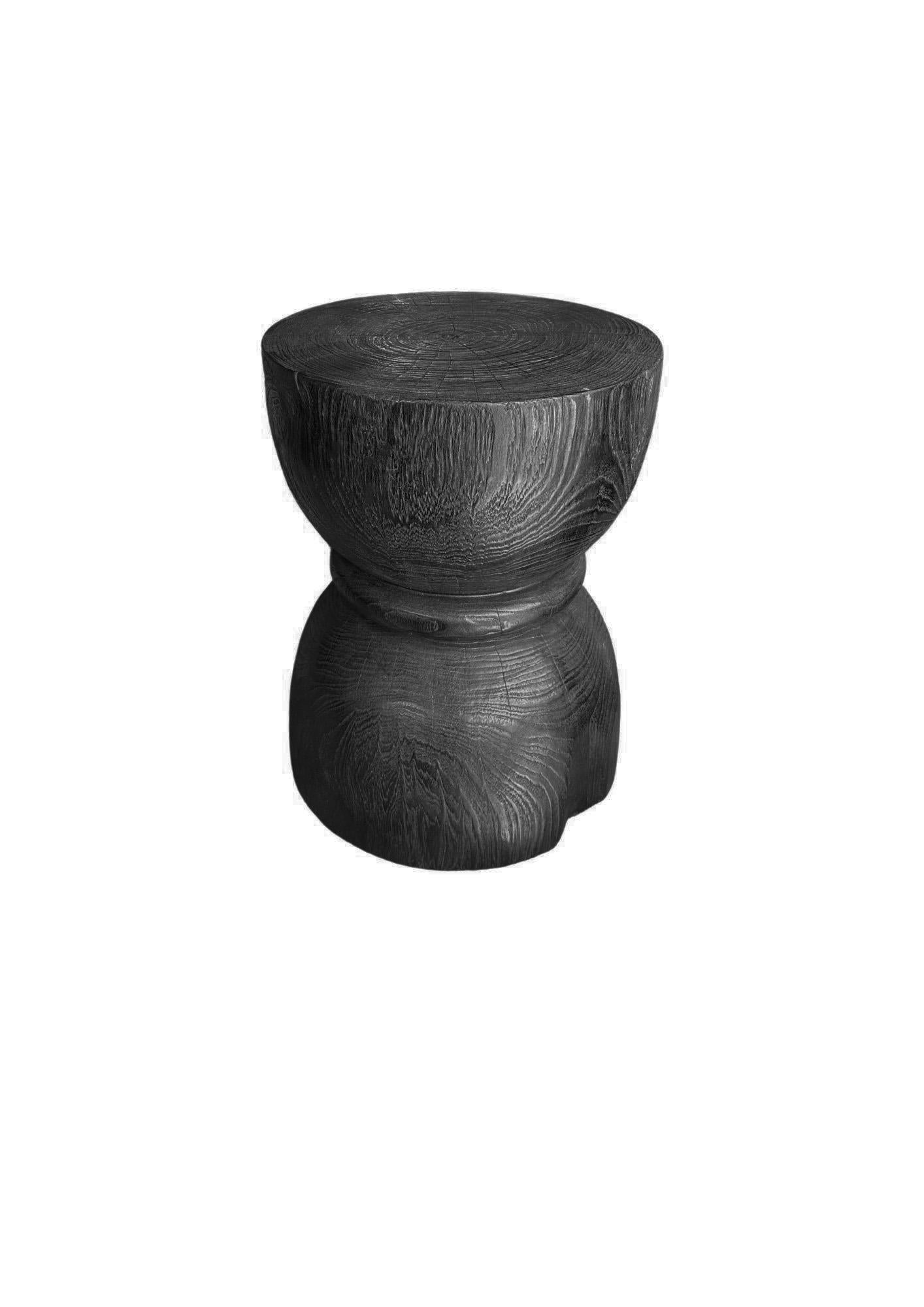 Une table d'appoint merveilleusement sculptée, fabriquée à partir d'un seul bloc de bois de teck. Il présente de merveilleuses textures de bois ainsi qu'une forme de sablier. Pour obtenir son pigment, le bois a été brûlé plusieurs fois et terminé