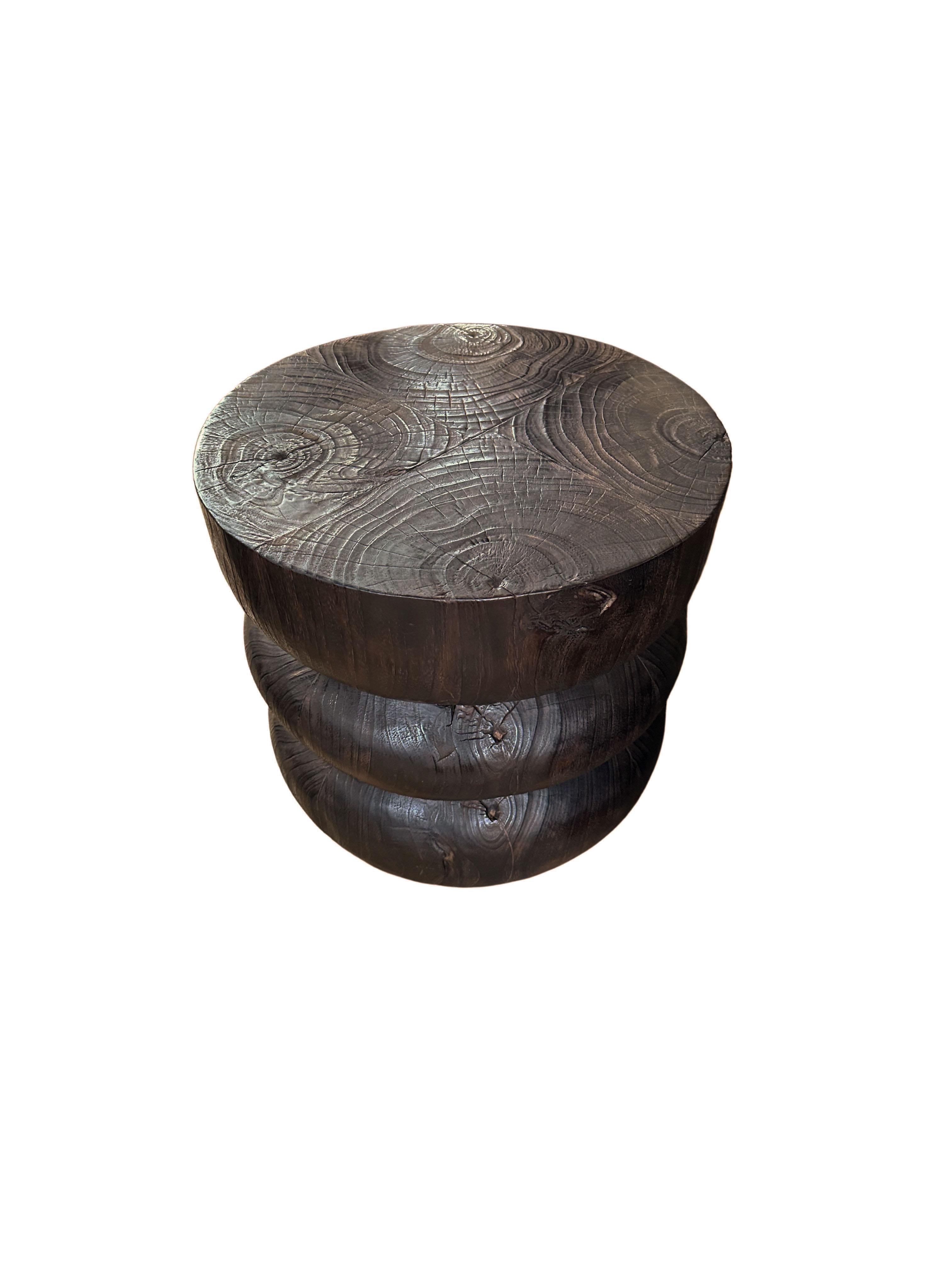 A wonderfully sculpted side table, crafted from a single block of teak wood. It features wonderful wood textures as well and carved detailing that wrap around its sides. To achieve its pigment the wood was burnt several times and finished with a