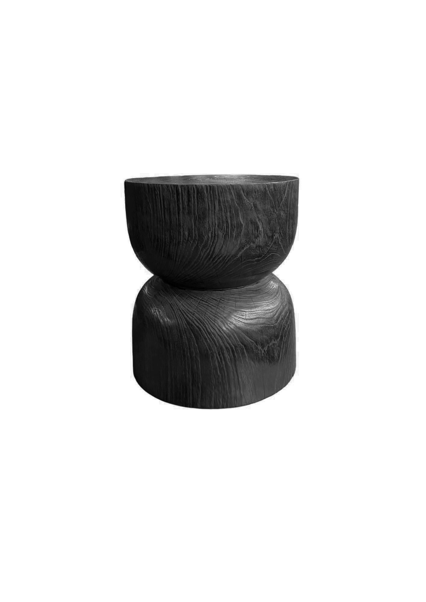 Elevate your space with the bold elegance of this teak side table, crafted to showcase the rich, natural textures of solid teak wood. Finished in a dramatic burnt black, the surface reveals intricate grain patterns and organic knots, adding depth