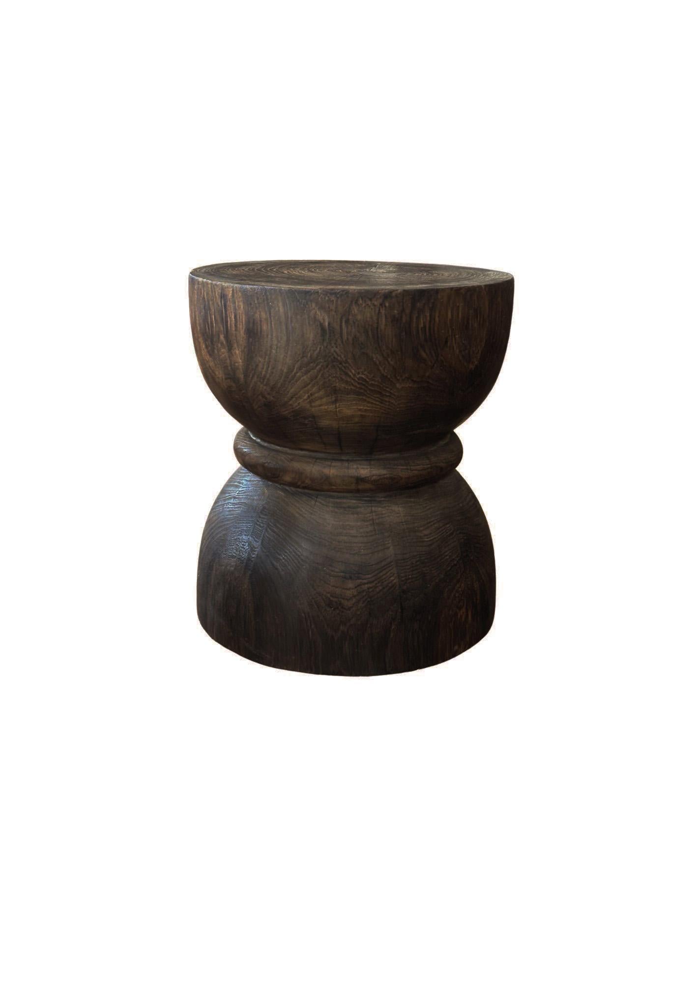 Une table d'appoint merveilleusement sculptée, fabriquée à partir d'un seul bloc de bois de teck. Il présente de merveilleuses textures de bois ainsi qu'une forme de sablier. Pour obtenir son pigment, le bois a été brûlé plusieurs fois et terminé