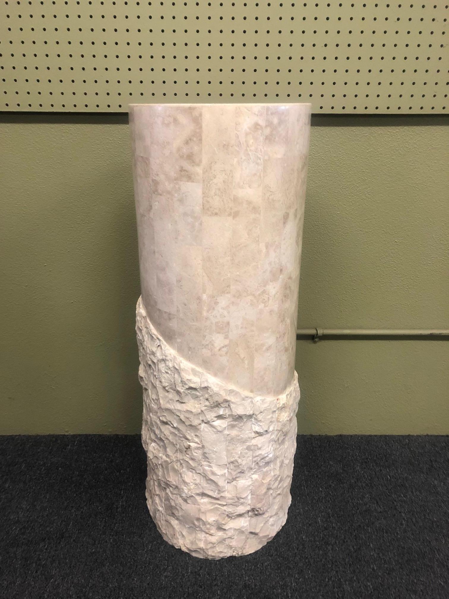 A very nice round tessellated stone display pedestal by Marquis of Beverly Hills, circa 1990s. The bottom portion of the piece has a rugged stone exterior that melds into the smooth, polished top portion.
 