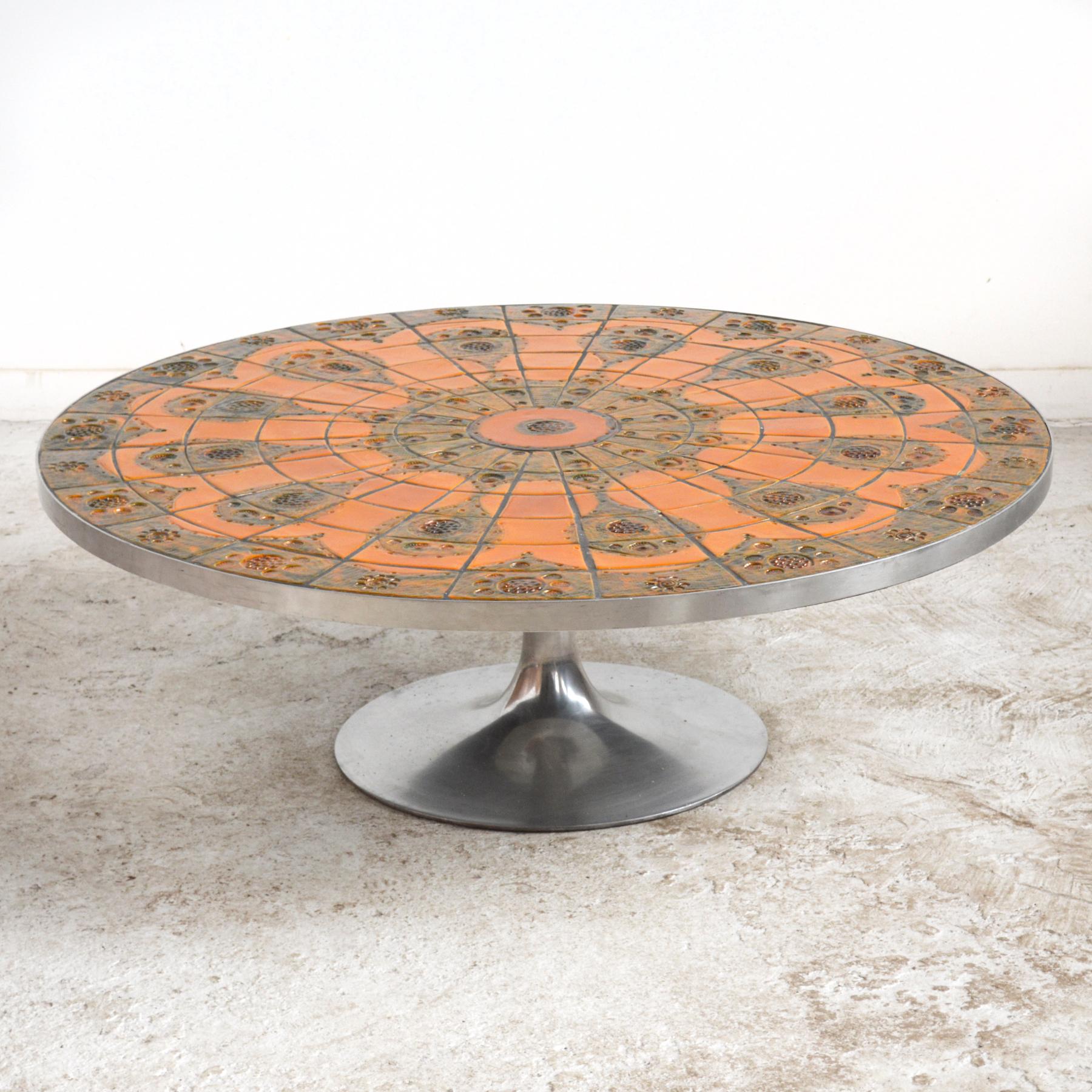 This striking Poul Cadovius coffee table has a stunning tile top by Lilly Just Lichtenberg in burnt orange and earth tones supported by an aluminum tulip style base. The wonderful abstract design will make it the centerpiece of any room.