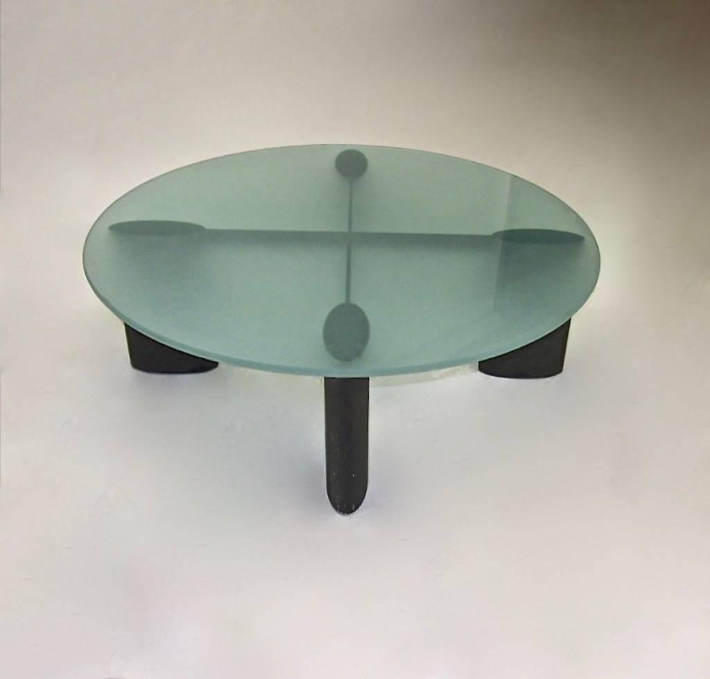 Coffee table, designed by Piotr Sierakowski for Koch and Lowy, has aluminum base that is made up of four elliptical legs in a charcoal gray finish connected by two  intersecting stretchers that supports a 42 inch round, sandblasted glass top.