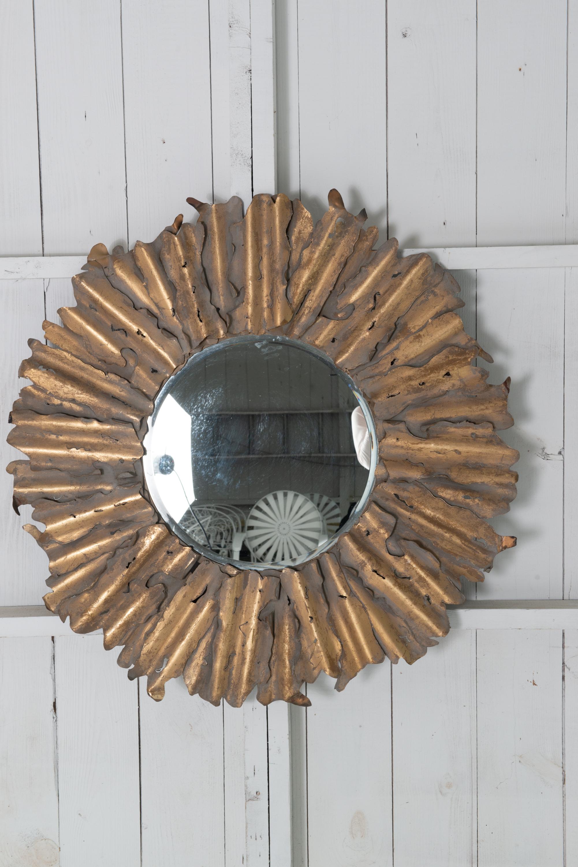 Miroir en laiton taillé au chalumeau, fabriqué à la main et stylisé en forme de soleil. Style brutal. Constitué de rayons de soleil individuels, vieillis et courbés, formant un grand miroir rond à effet soleil. La surface du miroir mesure à elle