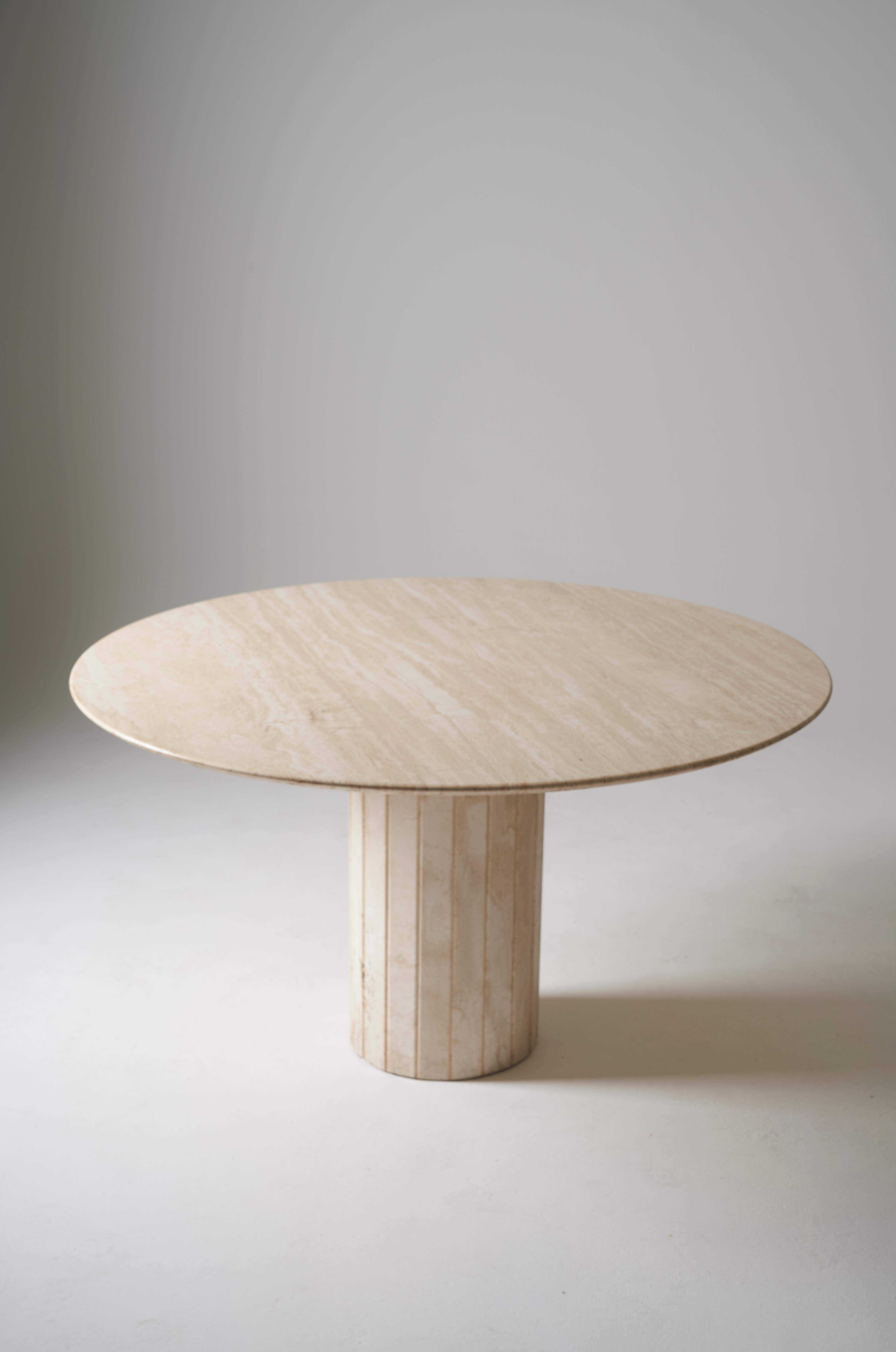 Travertine dining table from the 80s. The travertine has a beautiful grain and has been well maintained. Consists of a large round dissociable top supported by a columnar center leg.