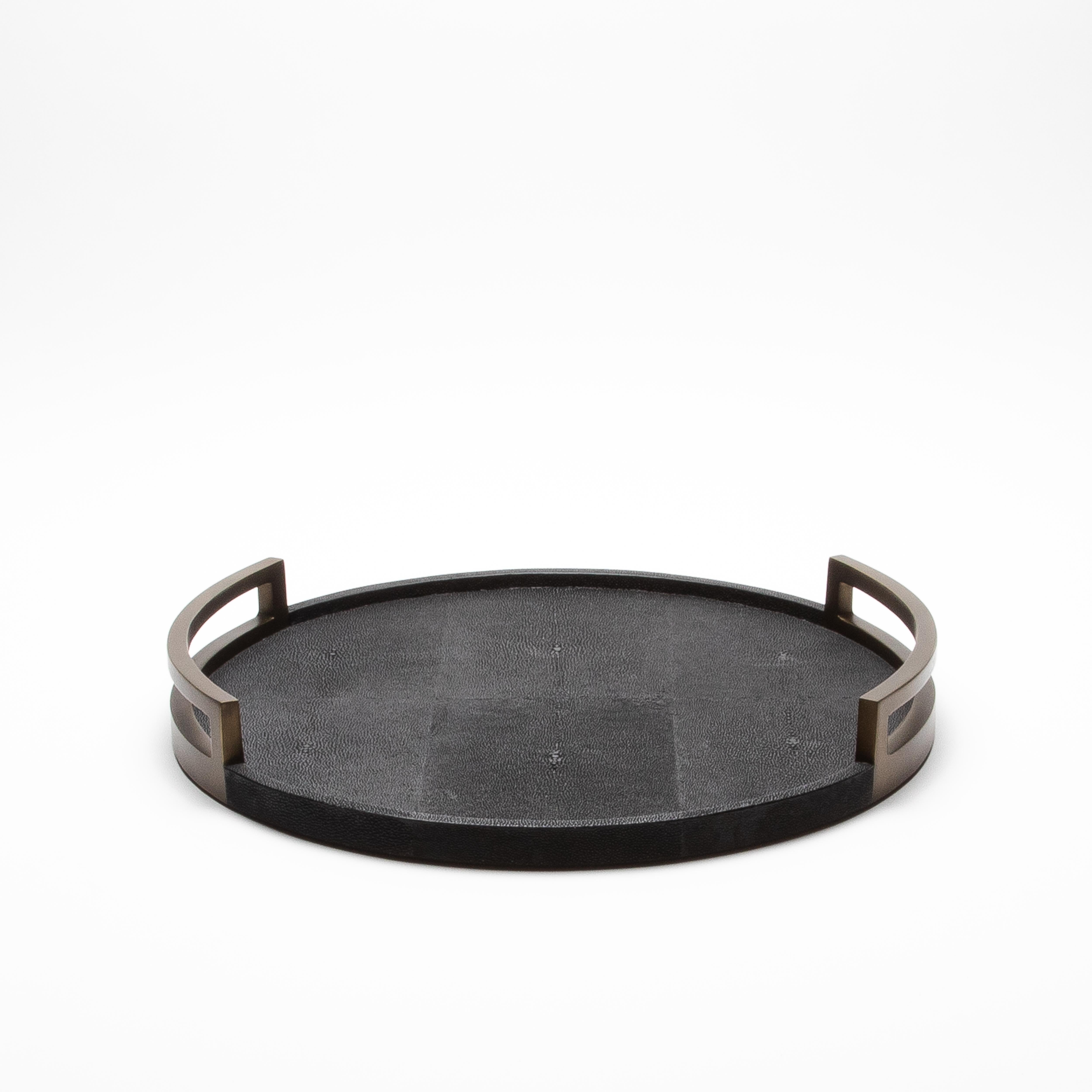 This round tray by R&Y Augousti is the epitome of opulence, where artistry and luxury converge in perfect harmony. The sumptuous black shagreen surface, with its rich, textured allure, evokes an air of sophistication, while the gleaming bronze