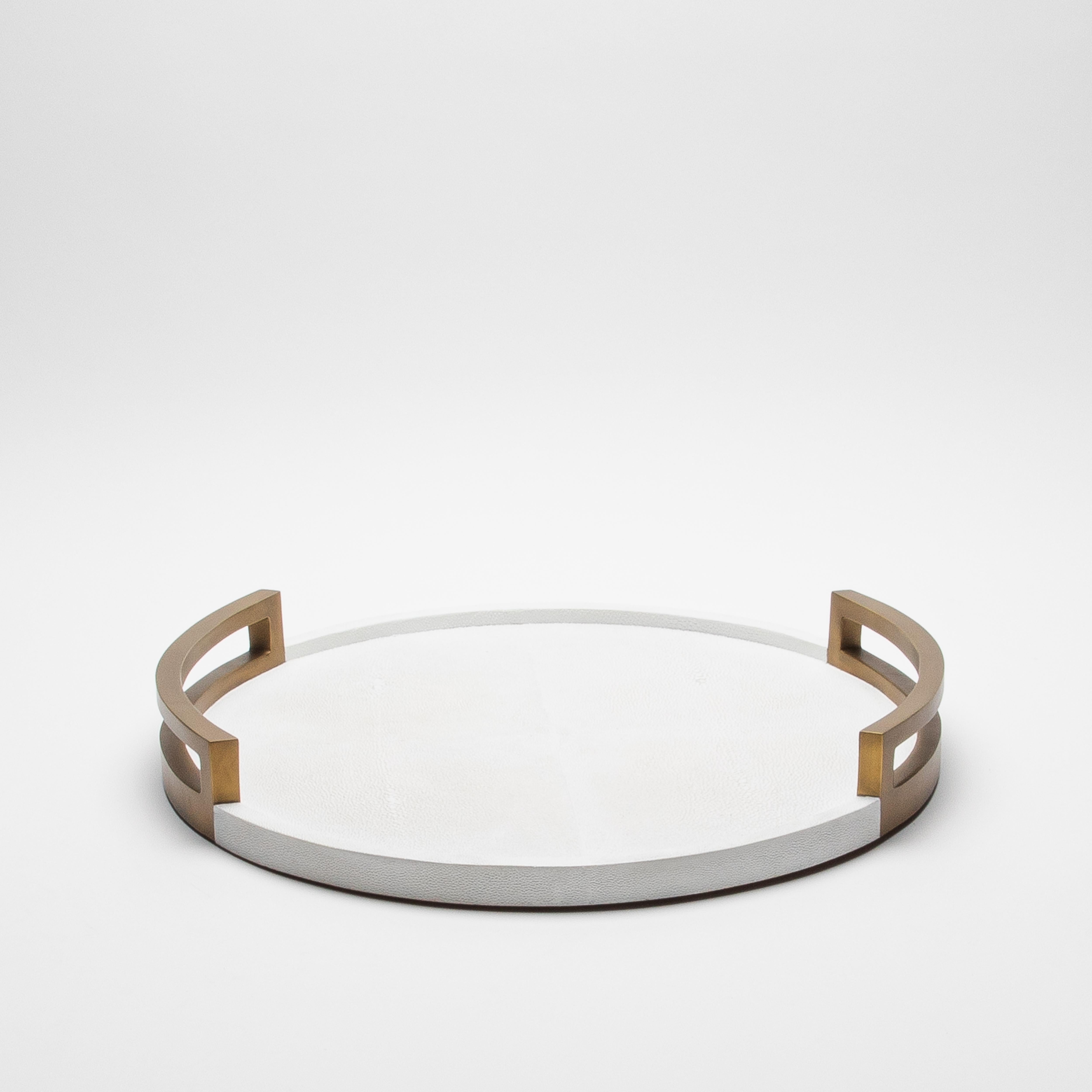 Ce plateau rond de R&Y Augousti est l'incarnation de l'opulence, où l'art et le luxe convergent en parfaite harmonie. La somptueuse surface en galuchat blanc, à l'allure riche et texturée, évoque un air de sophistication, tandis que les poignées en