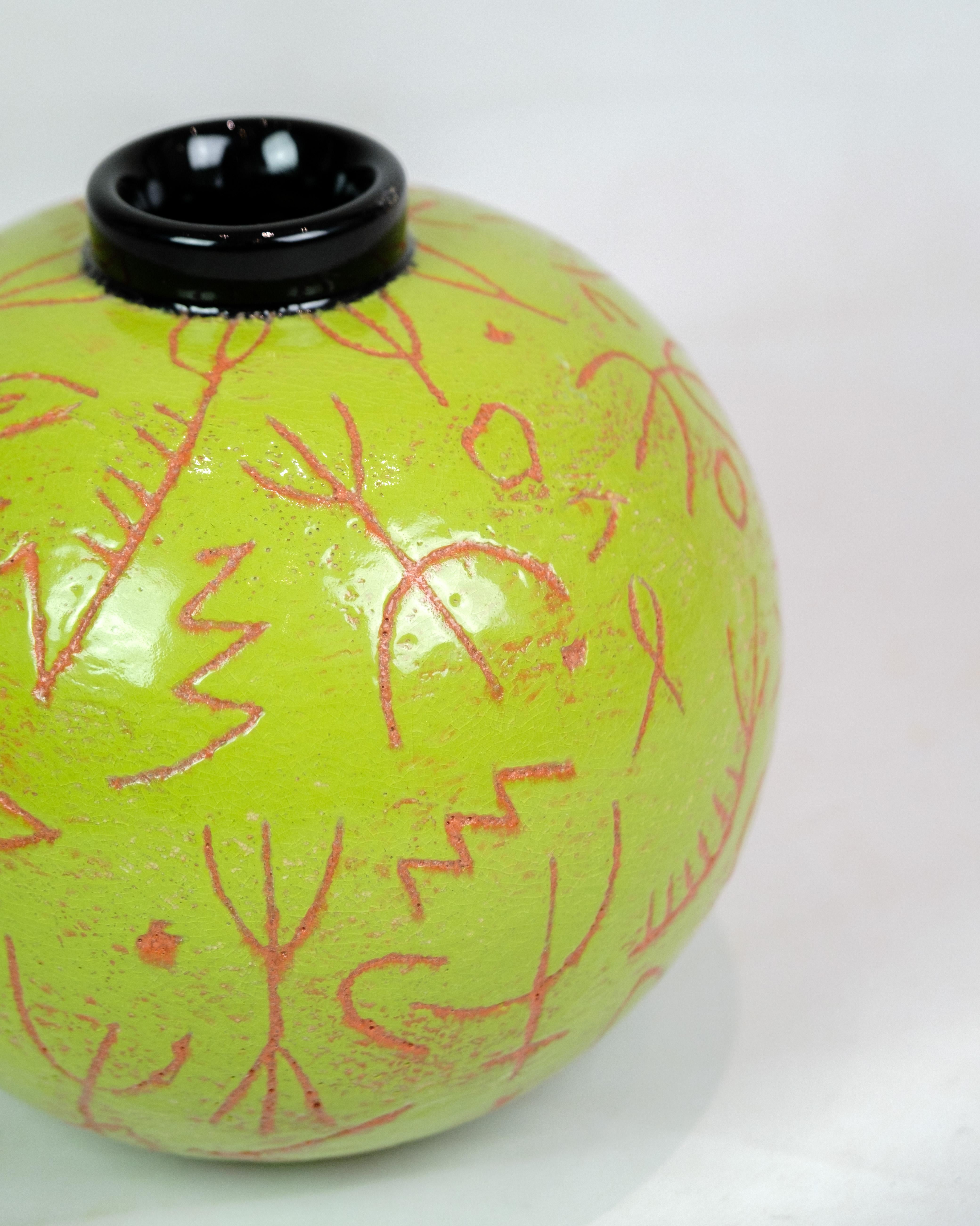 Die runde Vase von Lene Regius mit schwarzem Deckel, grüner Glasur und orangefarbener Mustergravur aus der Zeit um die 1990er Jahre repräsentiert eine einzigartige Periode im Keramikdesign. Die Vase kombiniert verschiedene Farben und Muster zu einem