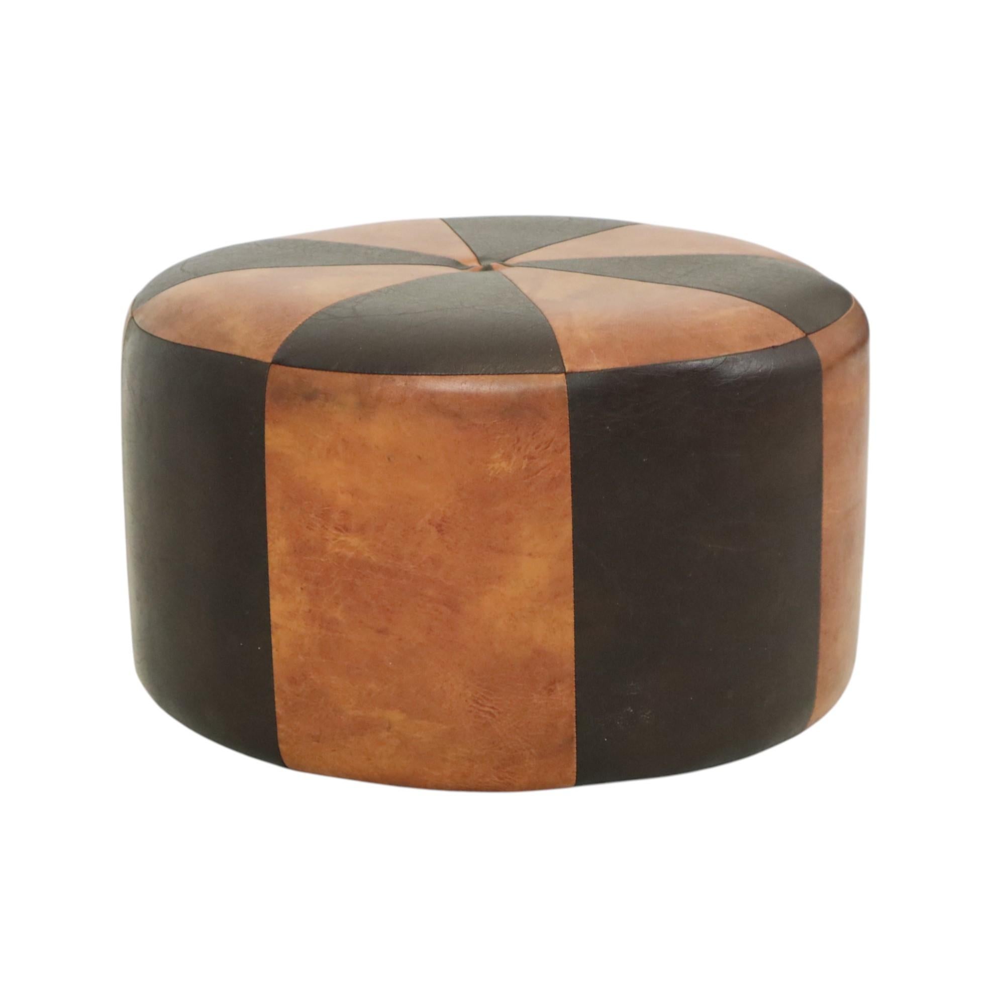 Cool round vintage patchwork ottoman, made from a wooden base and upholstered in high-quality two-tone brown faux leather, manufactured in Belgium circa the 1960s.

This ottoman is in good, used vintage condition with signs of wear and tear