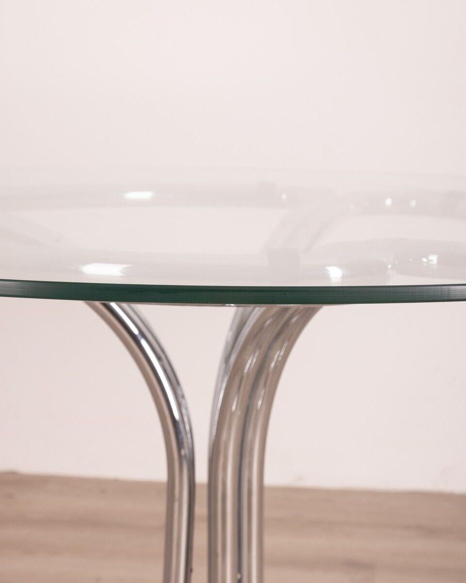 Round table with chromed tubular metal structure and glass top, 1970s.

CONDITION: In good condition, may show light signs of wear.

DIMENSIONS: height 71cm; diameter 100cm

MATERIALS: metal and glass

YEAR OF PRODUCTION: 1970s