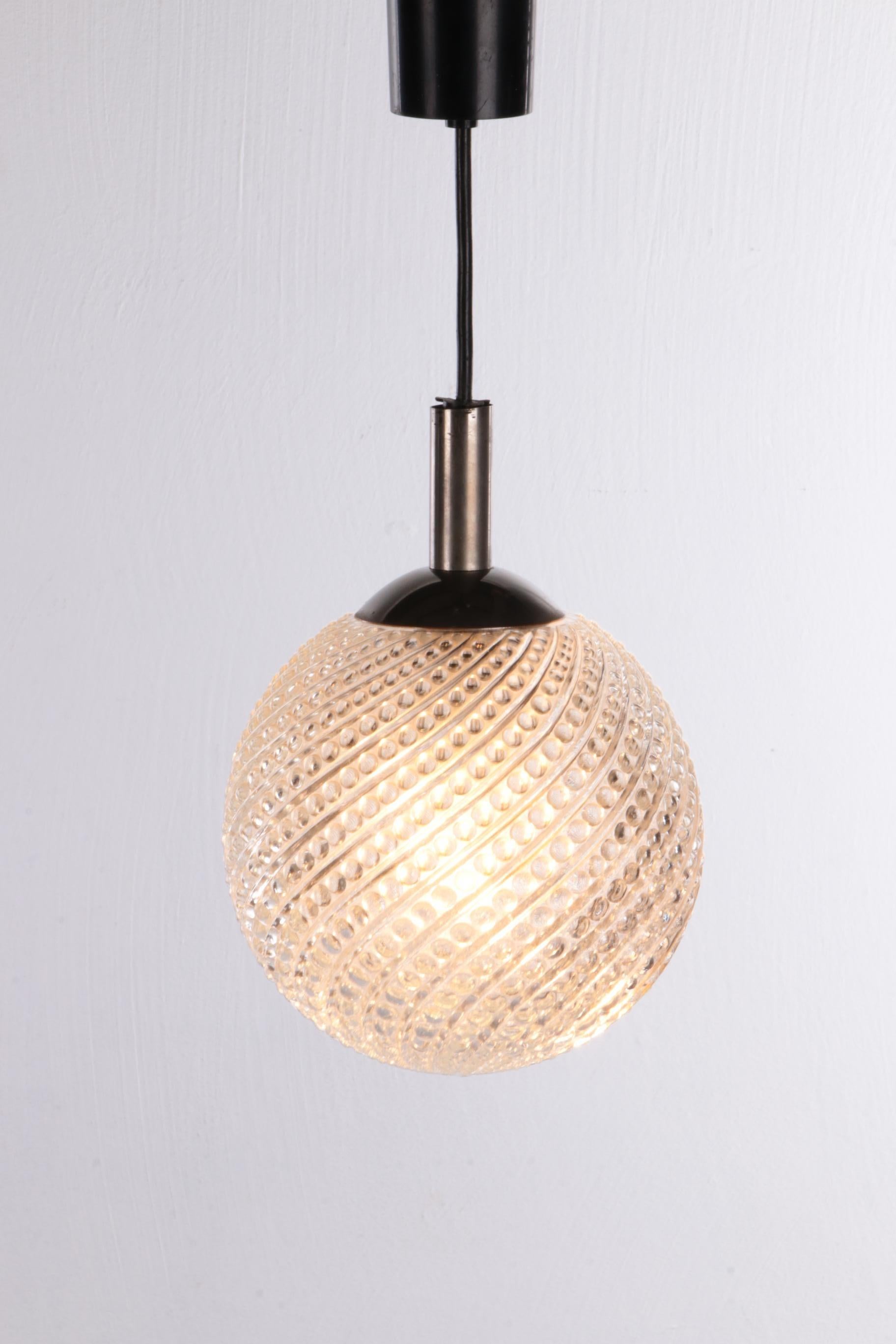 Beautiful pendant lamp from the sixties, made of metal and processed glass.

The lamp hangs from a black cord that ends in a metal fixture at the beginning of the sphere. The original glass sphere in which the light source hangs hangs from the