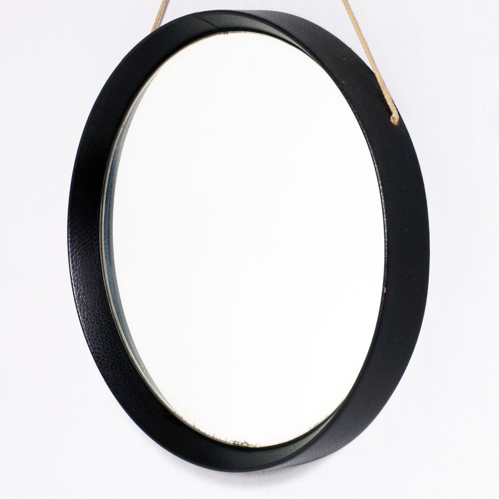 Round Wall Mirror, by Fontana Arte, wood frame leather covered, rope hanging. 
Very rare mirror of the Fontanit which was followed by numerous fashionable productions in Italy and throughout the world.
The hanging rope is worn in the part of