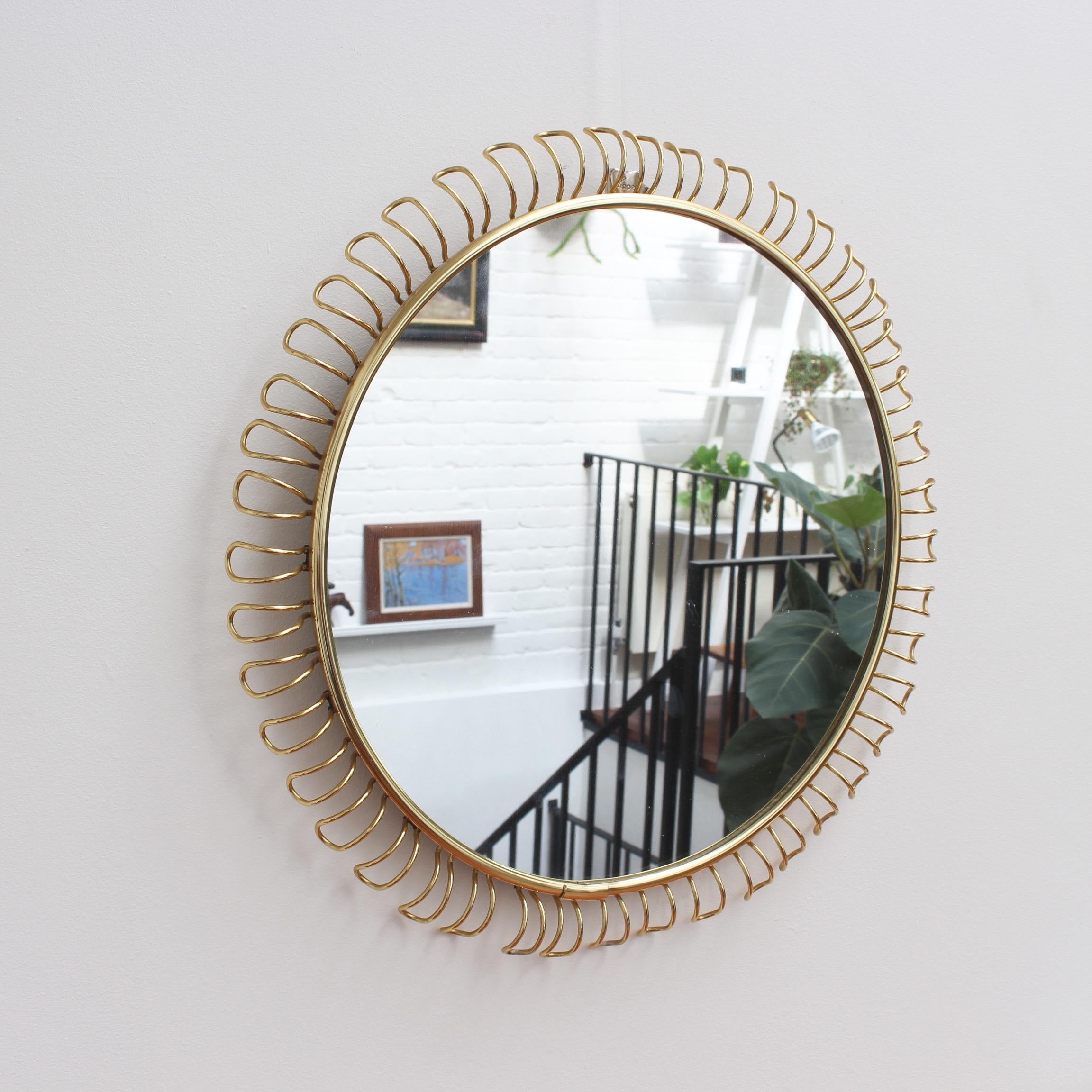 Round brass wall mirror with decorative corona-effect surround by Josef Frank (circa 1950s - 1960s). Original styling and elegant presence, this mirror is the centre of attention in any room. One of the decorative brass rectangular edging coils has