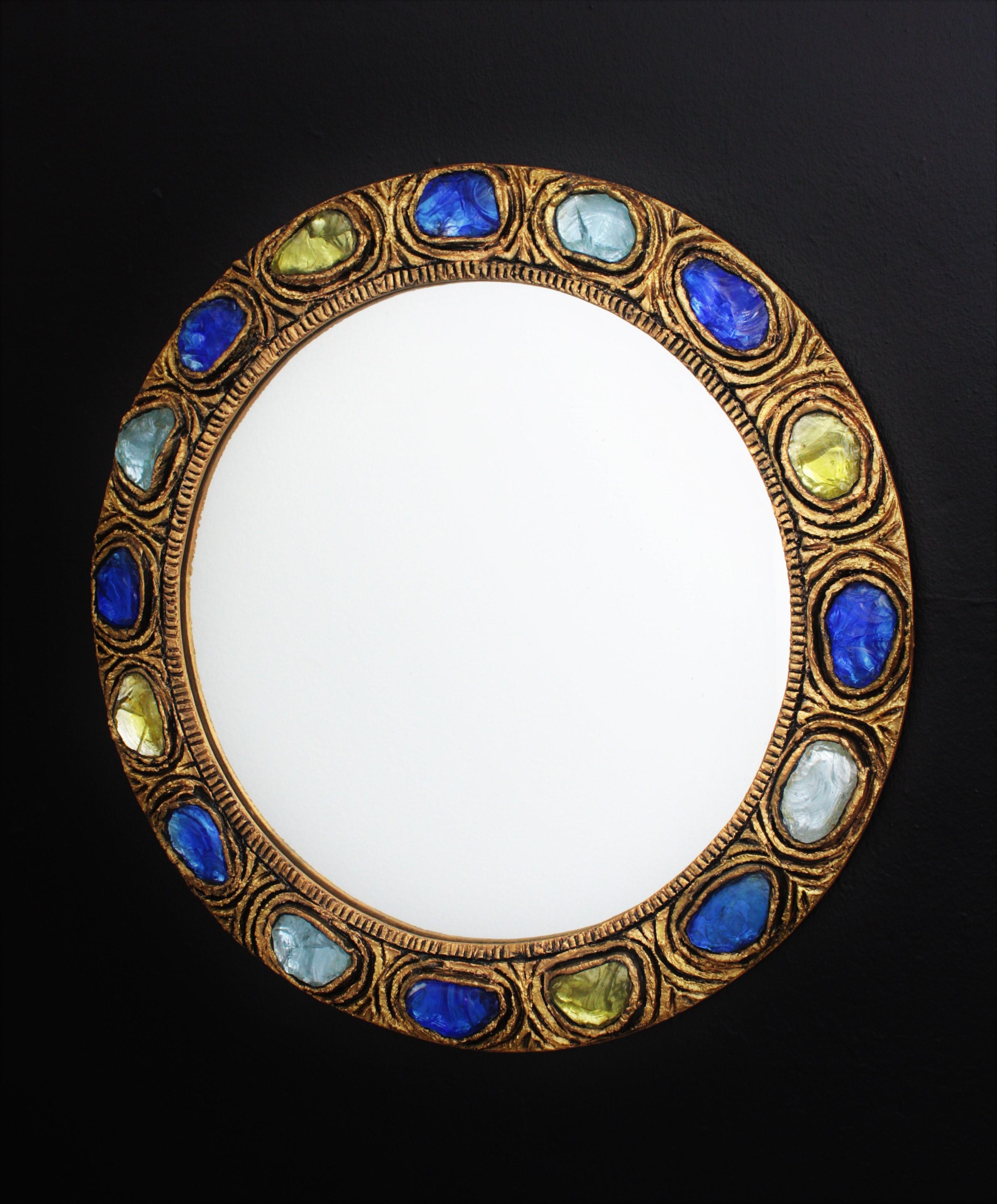 Rare Mid-Century Modern handcrafted circular mirror made of stucco accented with blue / purple and yellow rock crystals. Spain, 1960s.
Beautiful frame made with pieces of colorful rock crystals and gold patinated finish. Lovely to be used as a