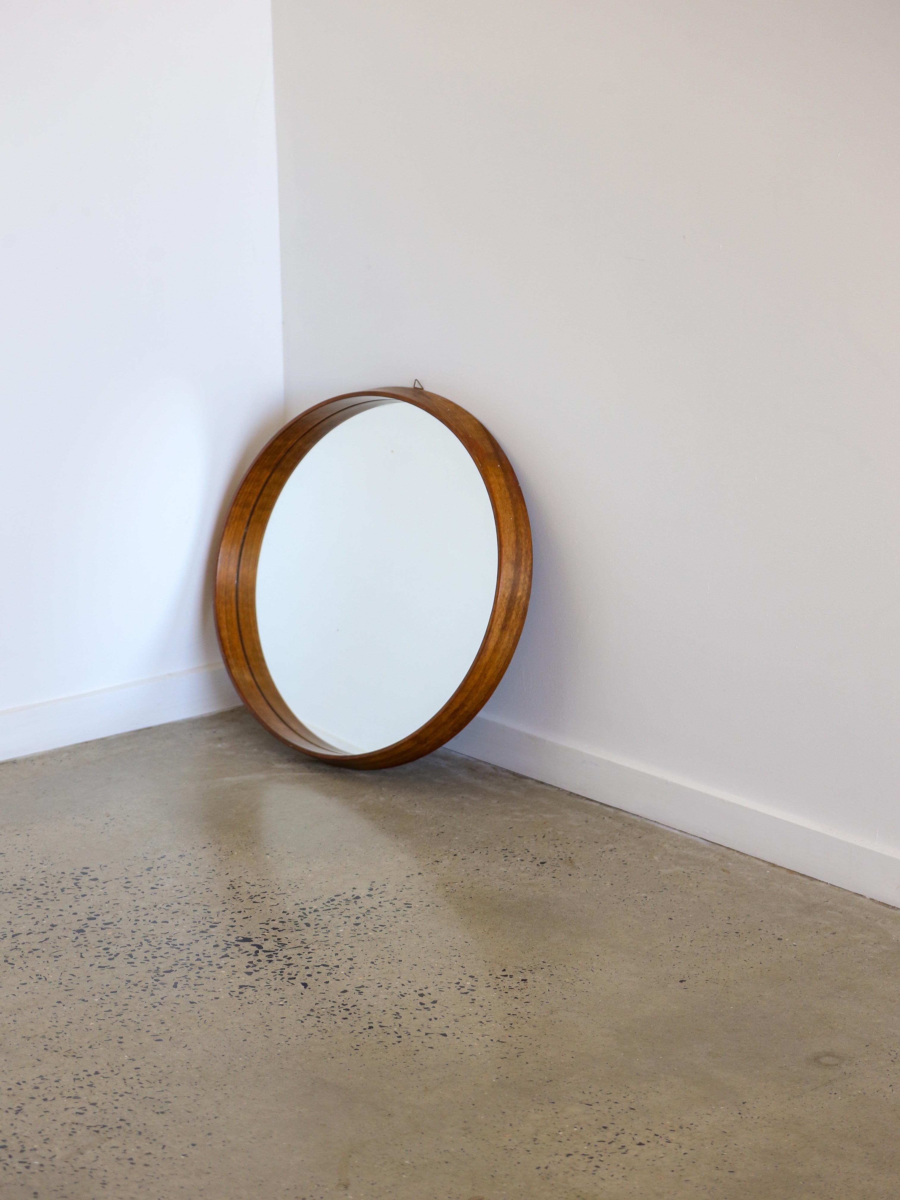 Italian Mid Century Modern round wall mirror.

The frame of the mirror is made from teak wood, which is known for its natural beauty and durability. Teakwood features a distinctive grain pattern and a warm, rich color that can add a touch of rustic