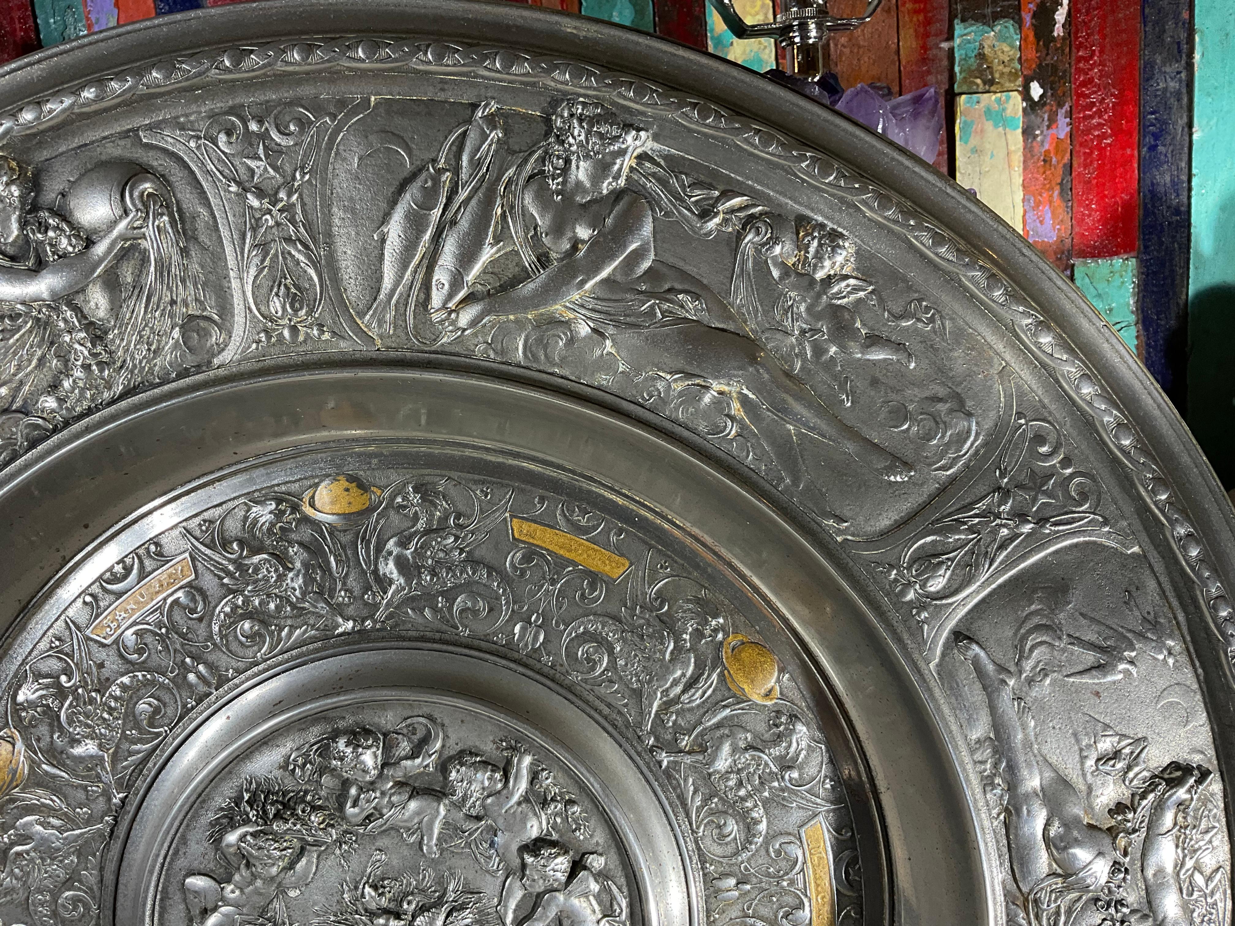 Beautiful round wall relief plate or center table tray, depicting allegoric scenes of the months of the year, decorated in figures, flowers and cartouches. Incredible fine chiseled details, made on cast metal silver plated. Could use on the table