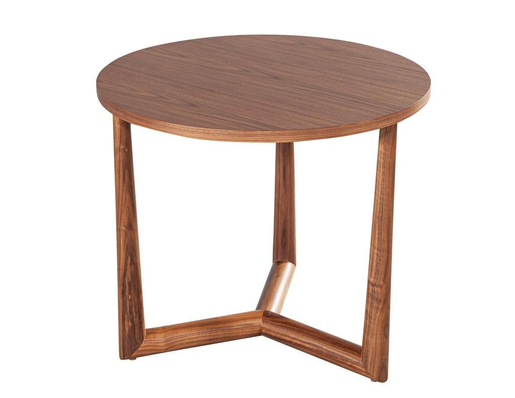 This round walnut side table is the perfect addition to any modern space. Crafted with mid-century modern inspirations and finished in a light warm walnut color palette with a satin sheen, this table is sure to add a touch of sophistication to any