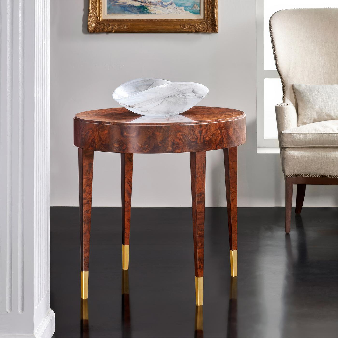 Showcasing beautiful walnut burl veneer. The table's circular top and clean-lined silhouette create a modern canvas that allows the wood's stunning natural patterns to take center stage. 

The elegant design is supported by four gracefully tapered
