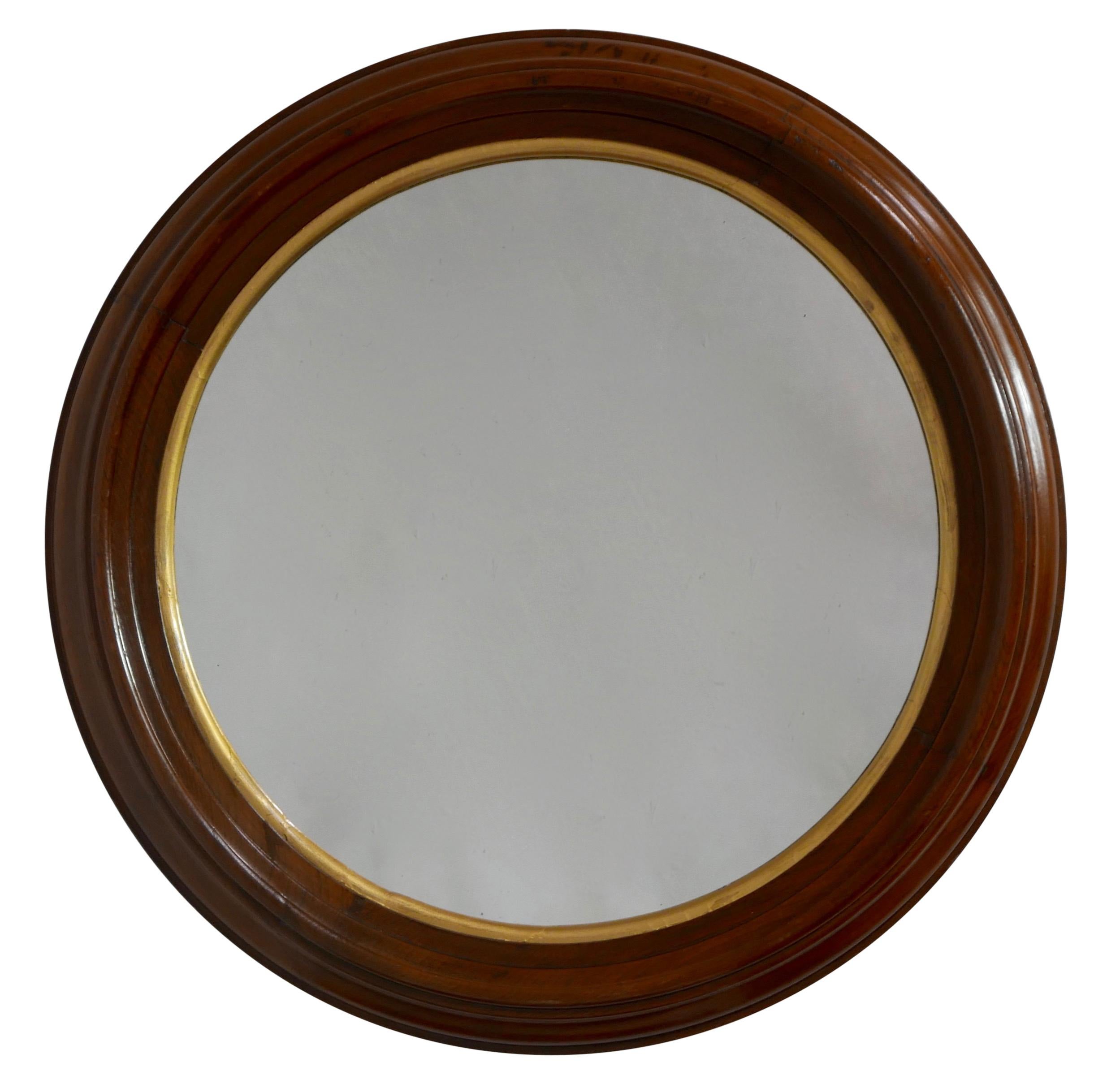 Circular walnut and parcel-gilt framed mirror, mortise and tenon construction of the multi carved walnut framed with an inner gilt band around the mirror plate. American, circa 1870.
  