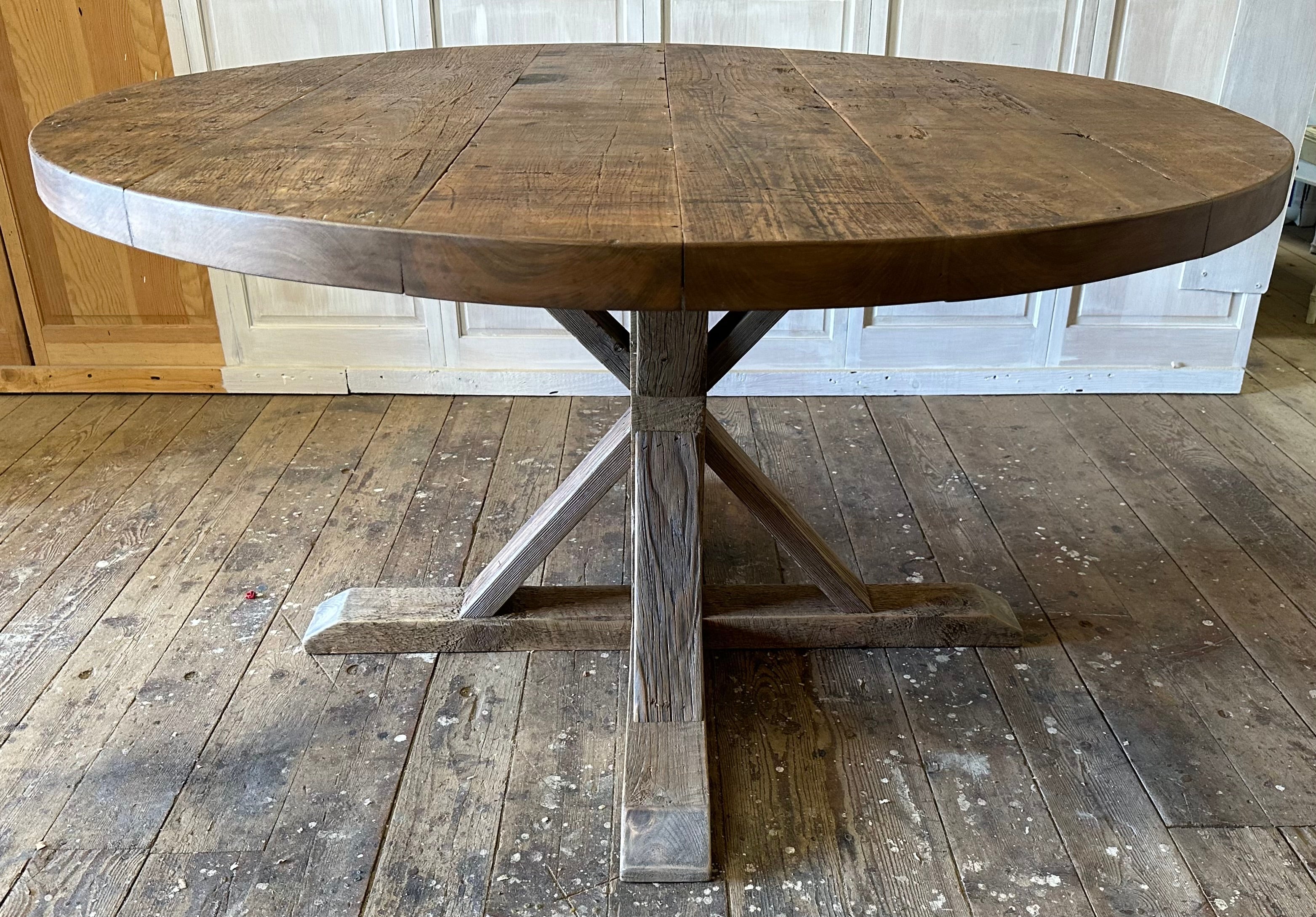 A timeless French inspired round pedestal farmhouse table made with reclaimed walnut table top and a newly crafted natural colored wood table base.  The table makes a perfect addition to any kitchen or dining room.  Natural and rustic in appearance,