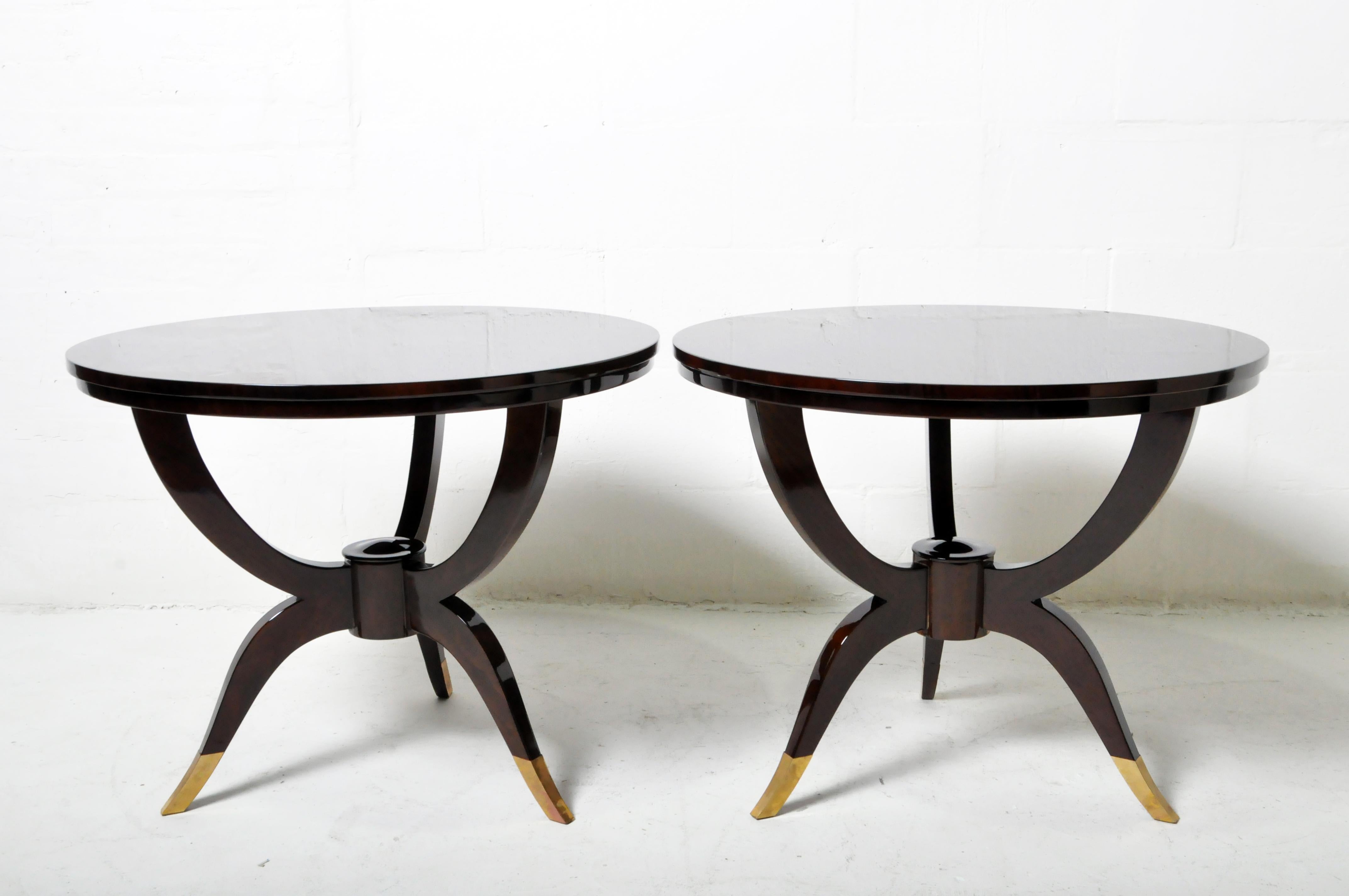 An elegant pair of curvaceous Art Deco French-style side tables in pie-matched walnut veneer. The feet are sheathed in brass.