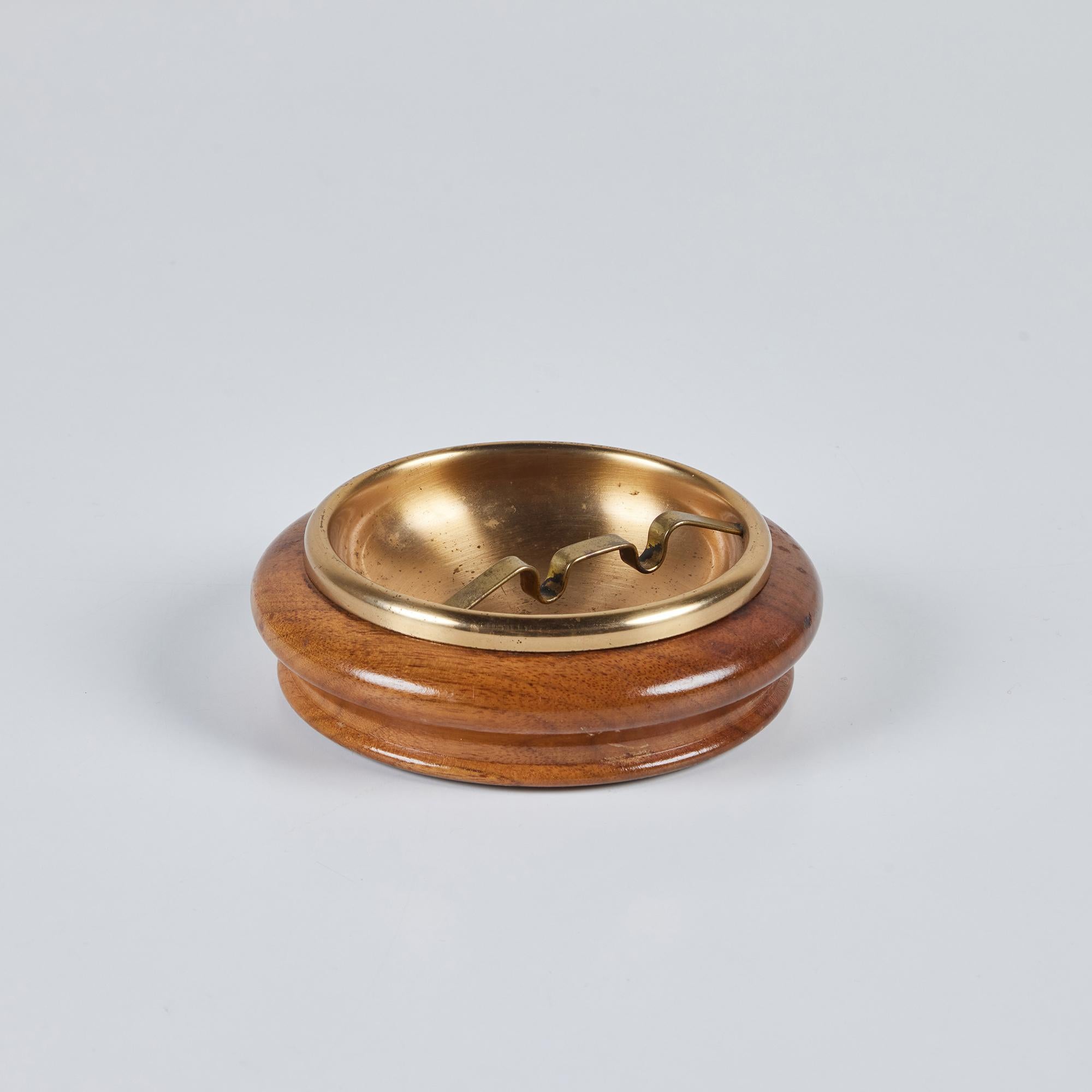 Round walnut ashtray c.1950s from Duk-It out of Buffalo, New York. This ashtray features a walnut exterior with brass insert. This piece can also be used as a vide poche or catchall to hold a myriad of things.

Dimensions
5.25