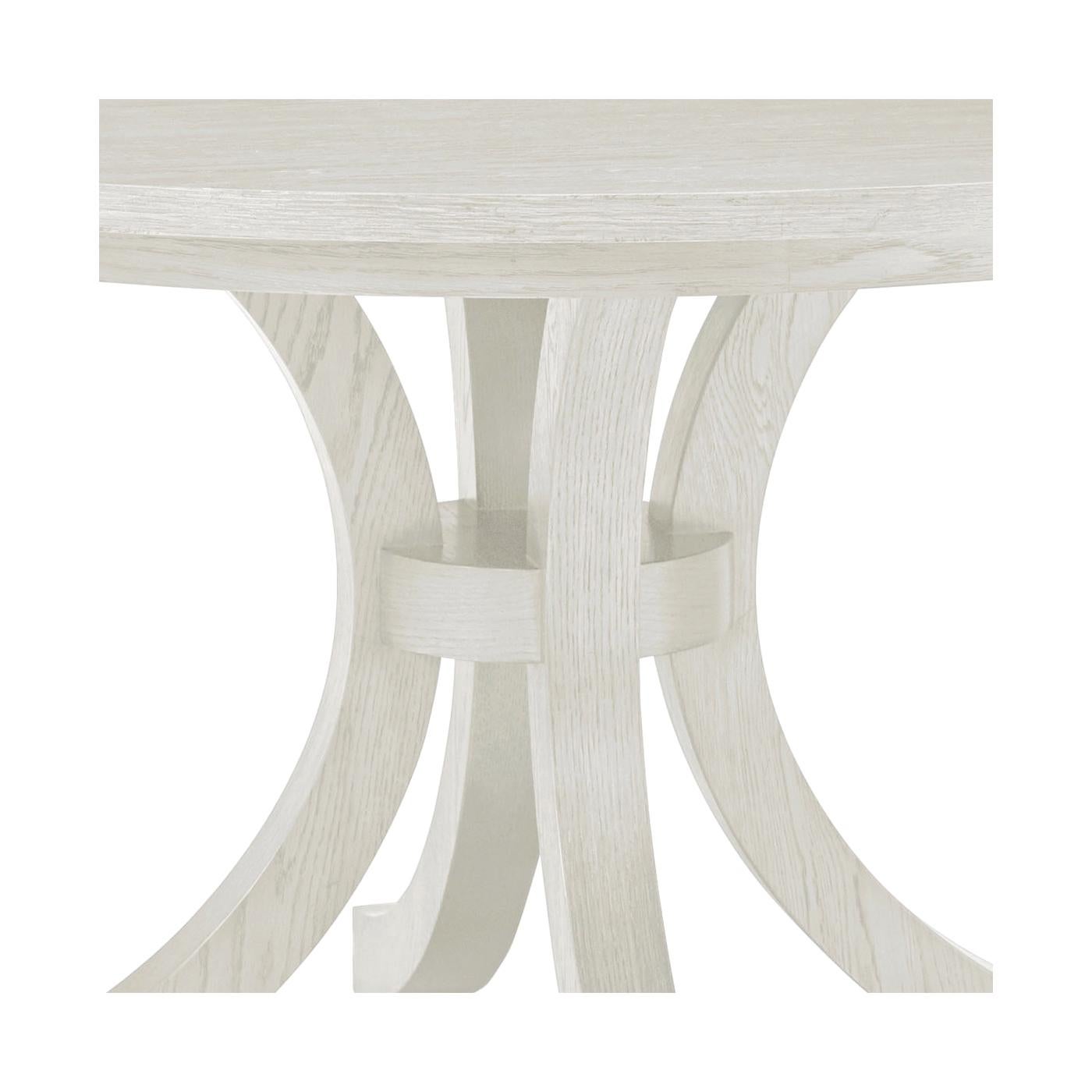 Realizzato in legno di quercia e rifinito con una pulita finitura bianco Dover, questo pezzo fonde l'artigianato tradizionale con una silhouette di ispirazione costiera. Il piano rotondo offre una presenza morbida e accogliente, rendendolo ideale
