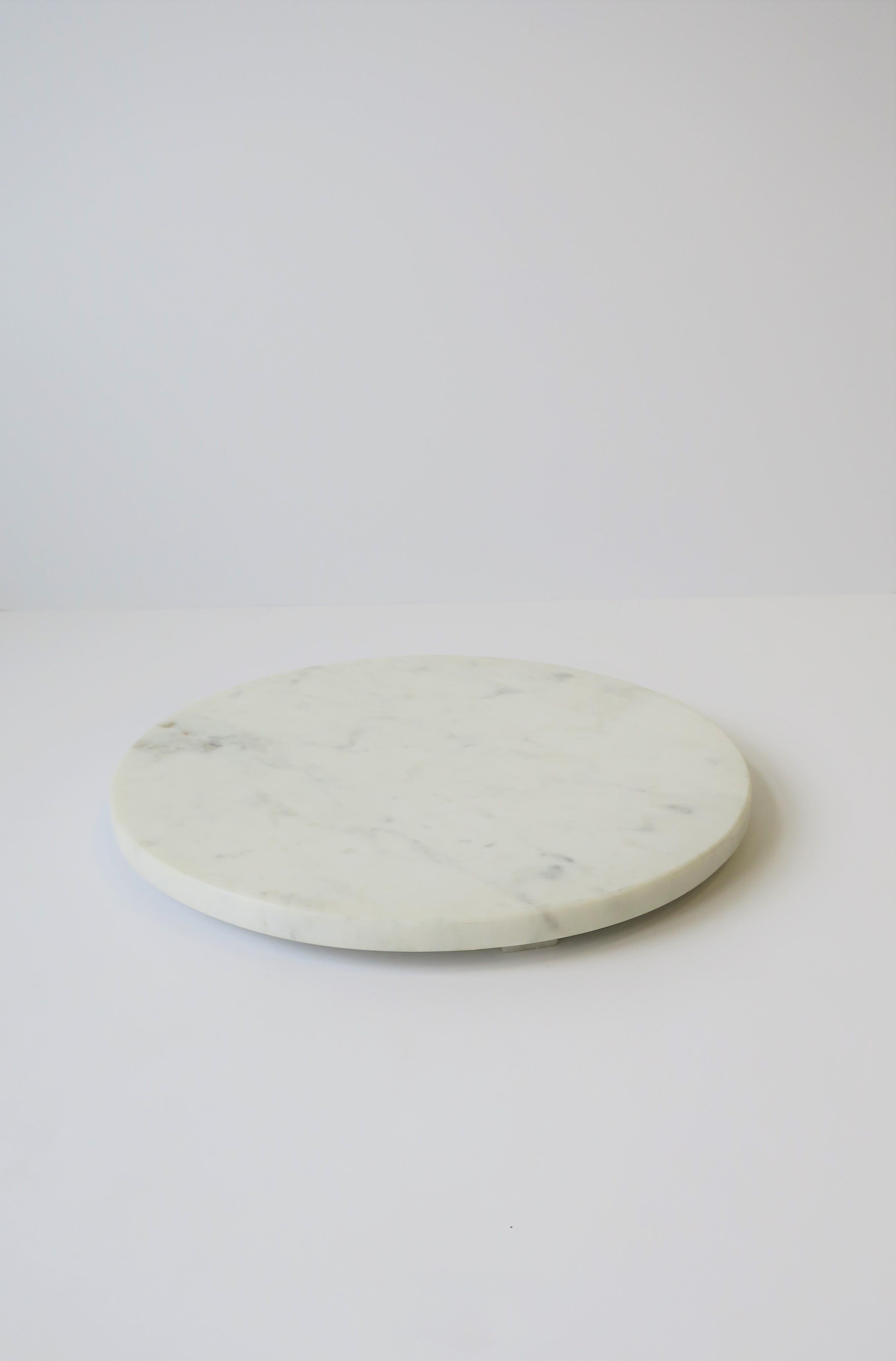 A round Modern or Minimalist style white marble trivet or tray, 21stth century. Marble is similar to Carrara marble but with tan and grey veining. Marble measures 1/2
