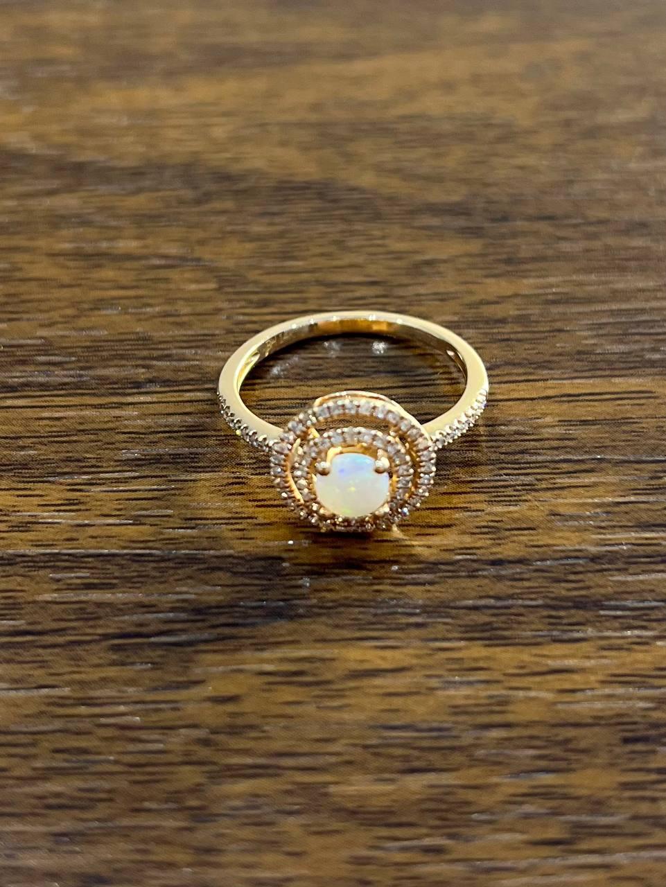 This exquisite piece features a captivating opal set in 14k yellow gold. The opal is encircled by two rows of sparkling diamonds, enhancing its iridescent beauty. The intricate halo design adds a touch of elegance and sophistication.
The band is