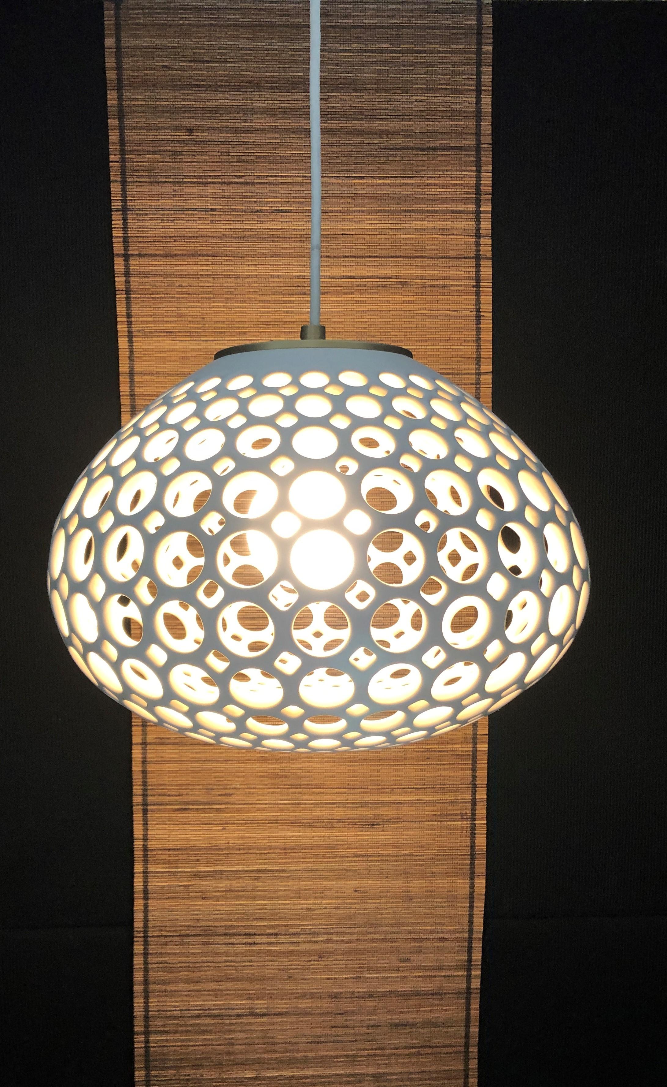 Wheel thrown, hand pierced pendant lamp, glazed with a white satin finish. This pendant has a white round silk cord and a plug for easy use, but can easily be permanently installed in your space. With a low watt bulb It is like a floating sculpture