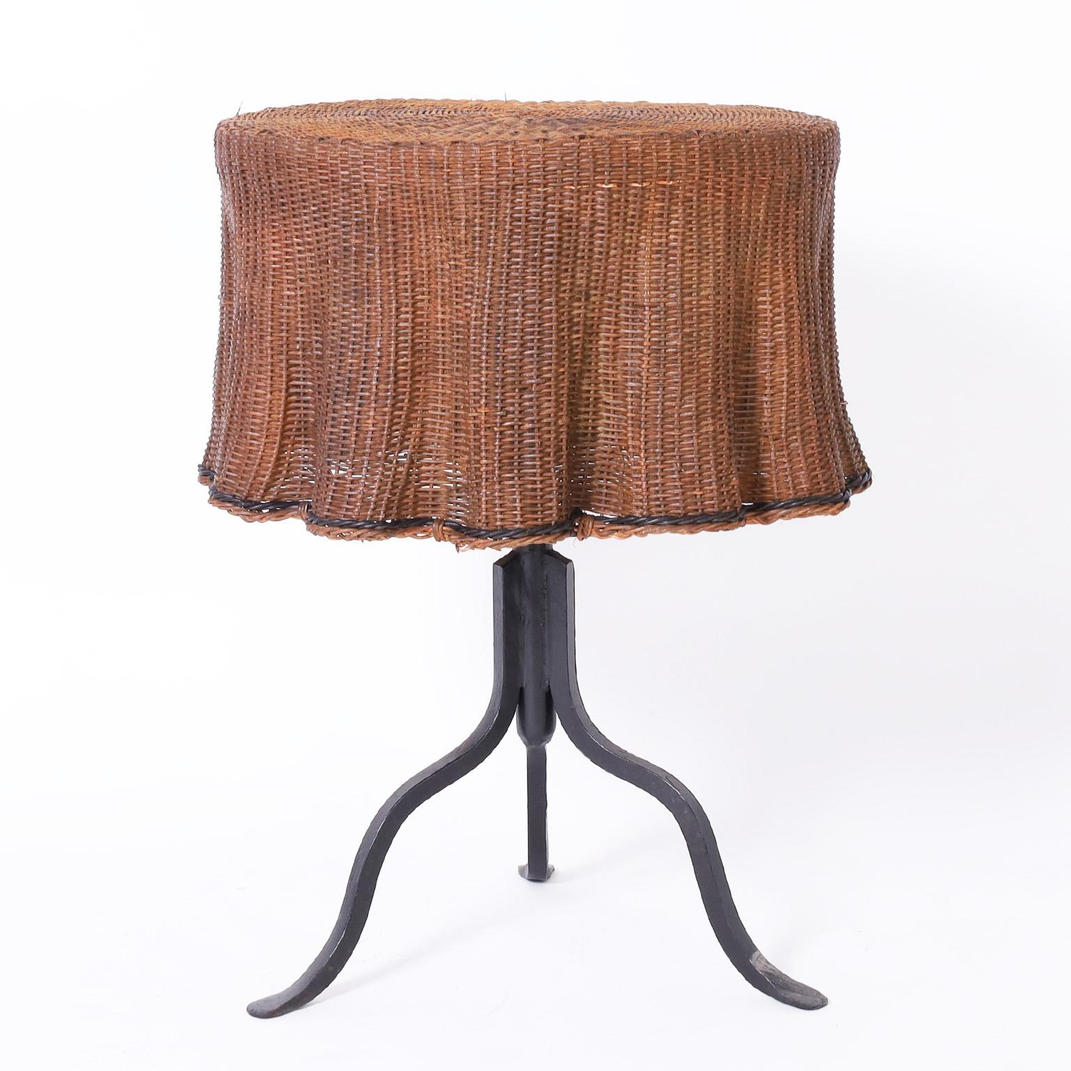 Unusual vintage occasional table with a ghost drapery top crafted in wicker on an iron base having three cabriole legs.