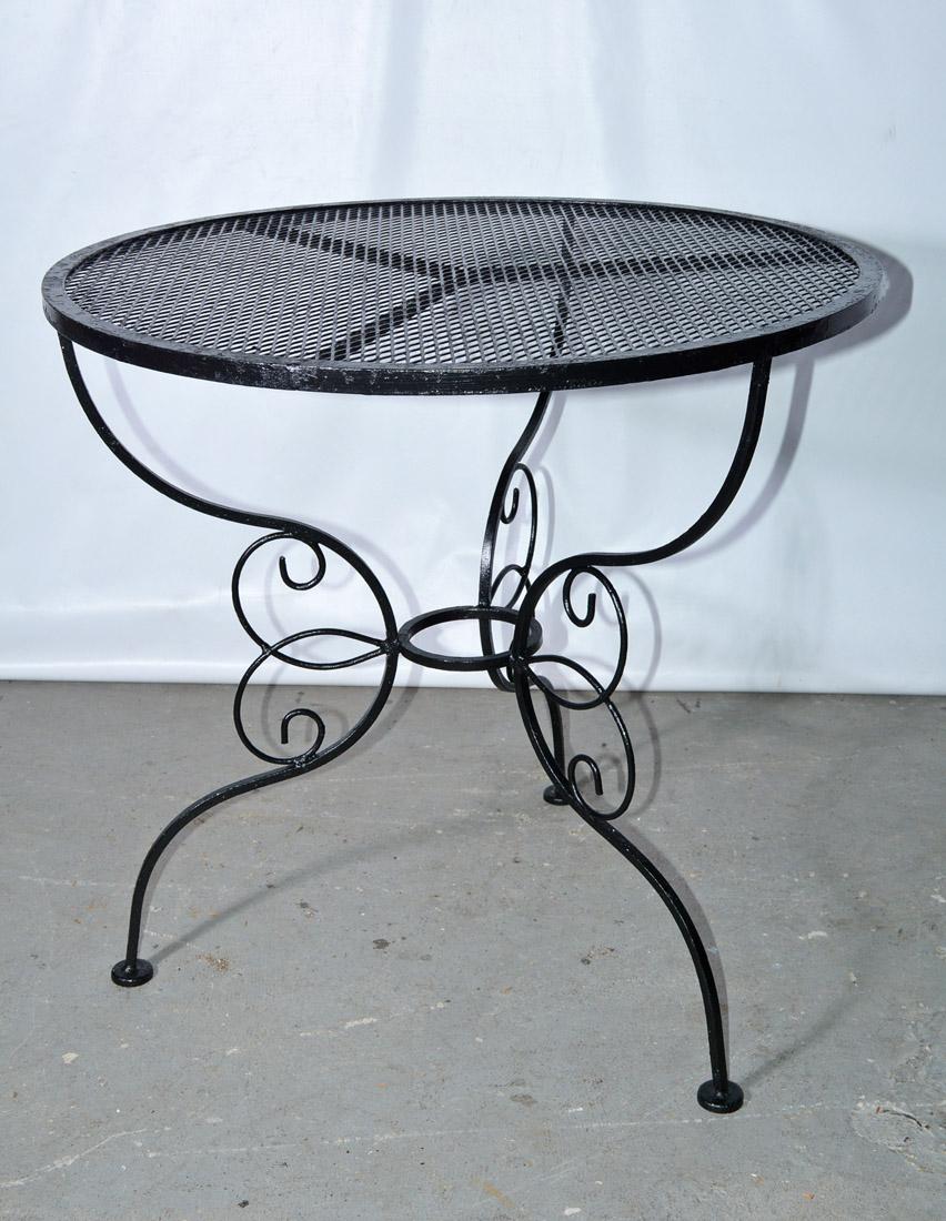 Vintage round outdoor/patio side table with iron scrolling base and steel mesh top by the Woodward Company. The table can be repainted in your choice of color.