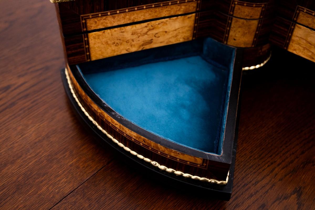 Boîte à bijoux décorative en bois. Fabriqué en bois de noyer avec des éléments métalliques. La boîte a été rénovée, doublée d'un nouveau tissu bleu. La boîte comporte des compartiments pour les bagues et autres bijoux.

Très bon état,